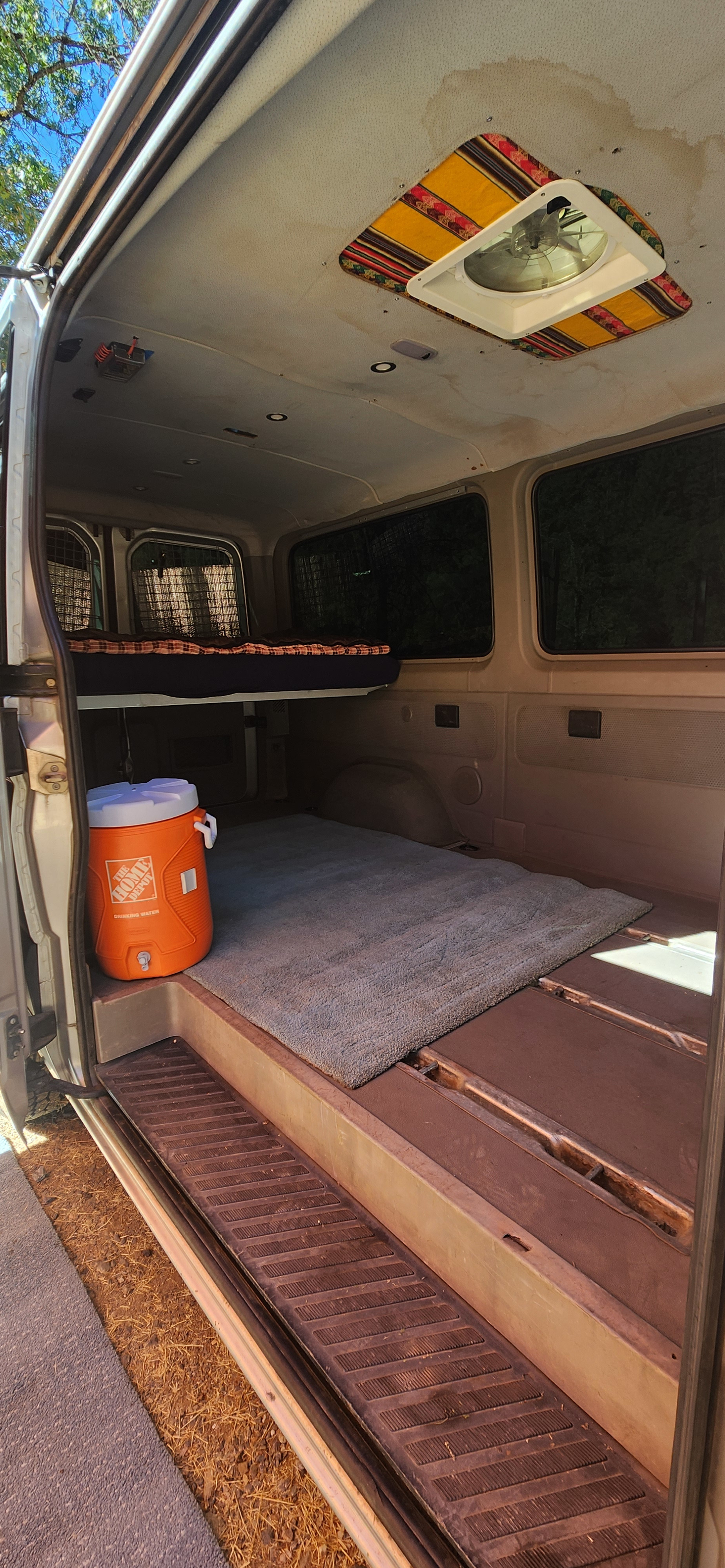 Explore this RV rental van's cozy interior: elevated bed, Home Depot cooler, rug, and decorative ceiling fan.. Dodge Sprinter Van 2007