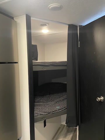 Cozy bunk beds inside an RV rental, featuring dark bedding and a privacy curtain for comfortable sleeping in a compact space.. Coachmen 257 BHS 2021