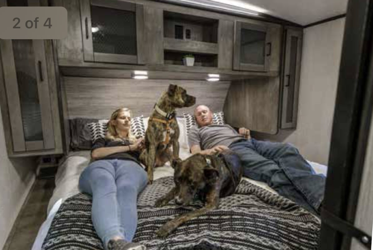 Cozy RV rental bedroom with a couple and two dogs relaxing. Ideal for pet-friendly RV travel.. Heartland RVs North Trail 2021