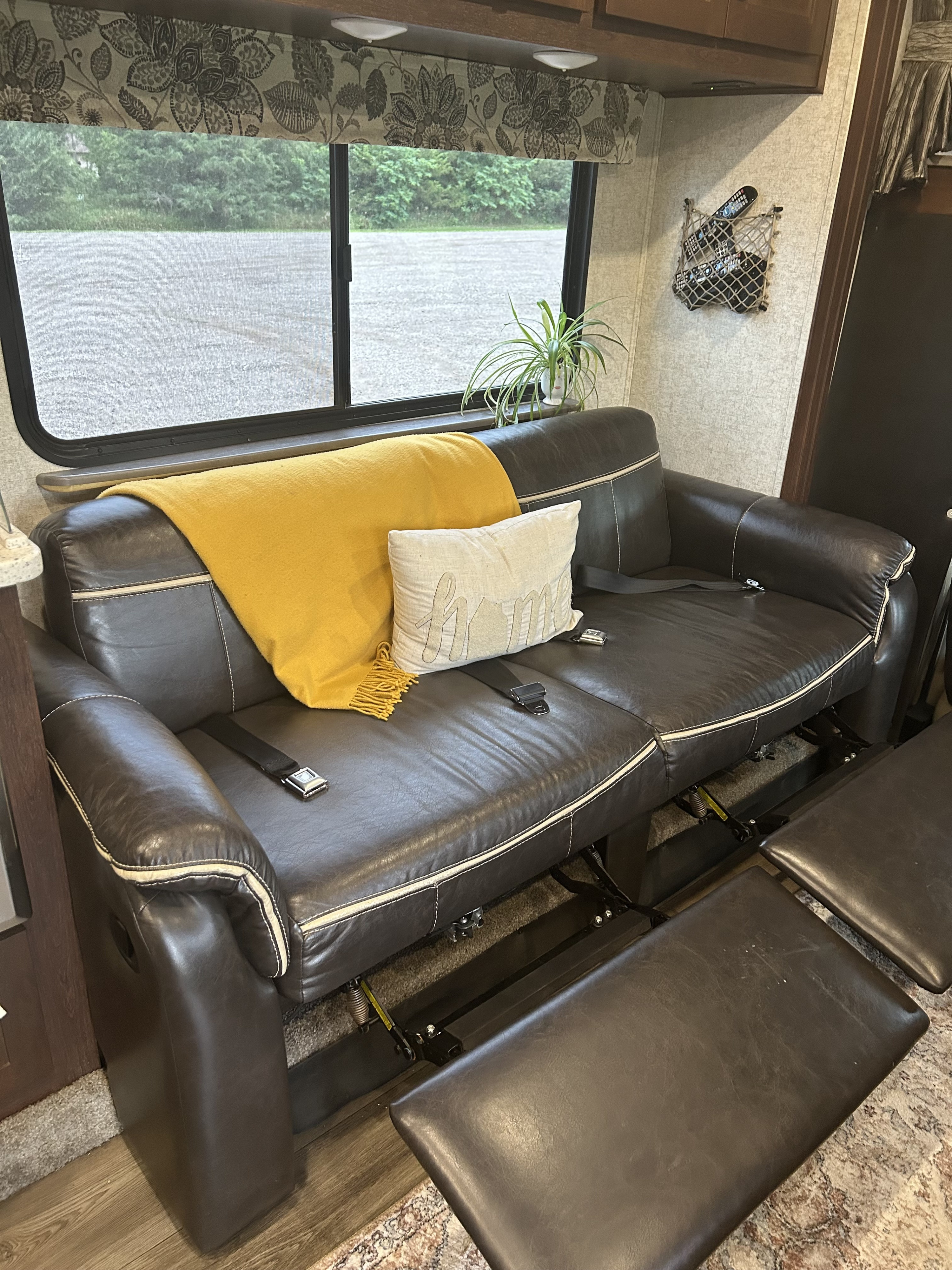 Comfortable brown leather sofa with recliners and seatbelts inside an RV rental, offering cozy travel living.. Forester Forester Motorhome 2017