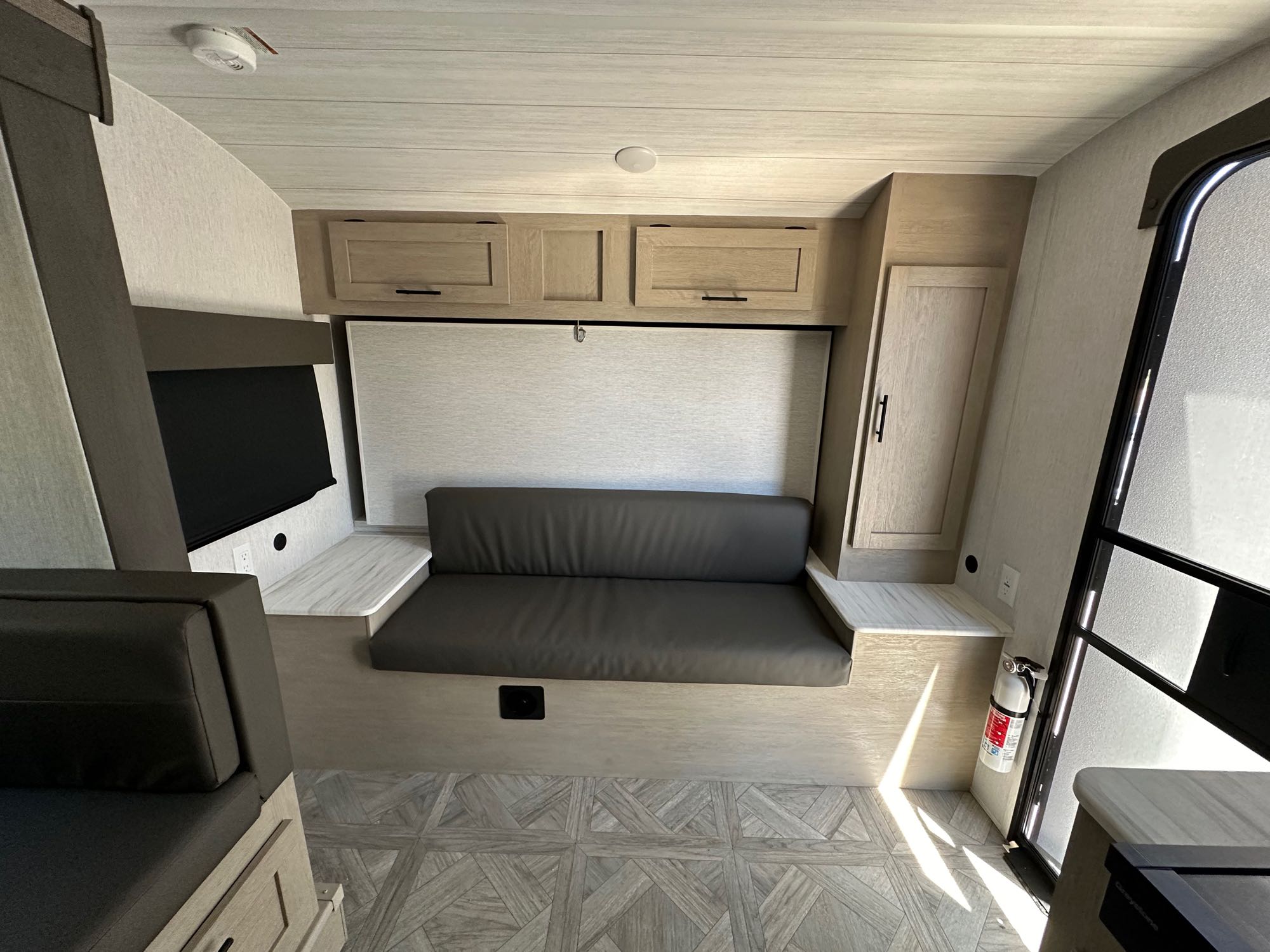 Spacious RV rental interior with comfortable seating, a wall-mounted TV, overhead storage, and light wood-look flooring.. Forest River Wildwood Platinum 2024