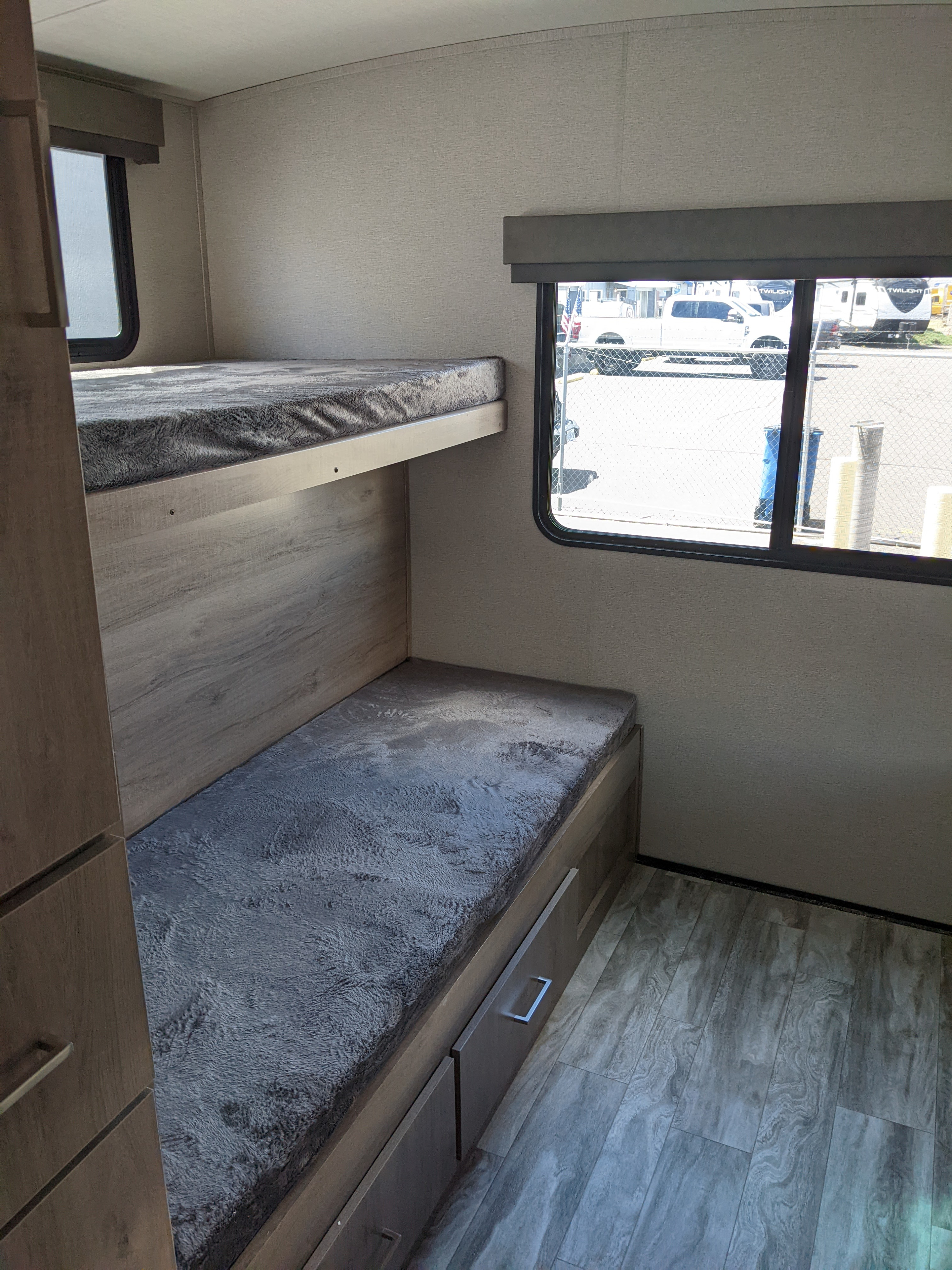 An RV rental's cozy bunk bed area, featuring a top and bottom bunk with gray fuzzy mattresses and under-bed storage drawers.. Grand Design Imagine 2022