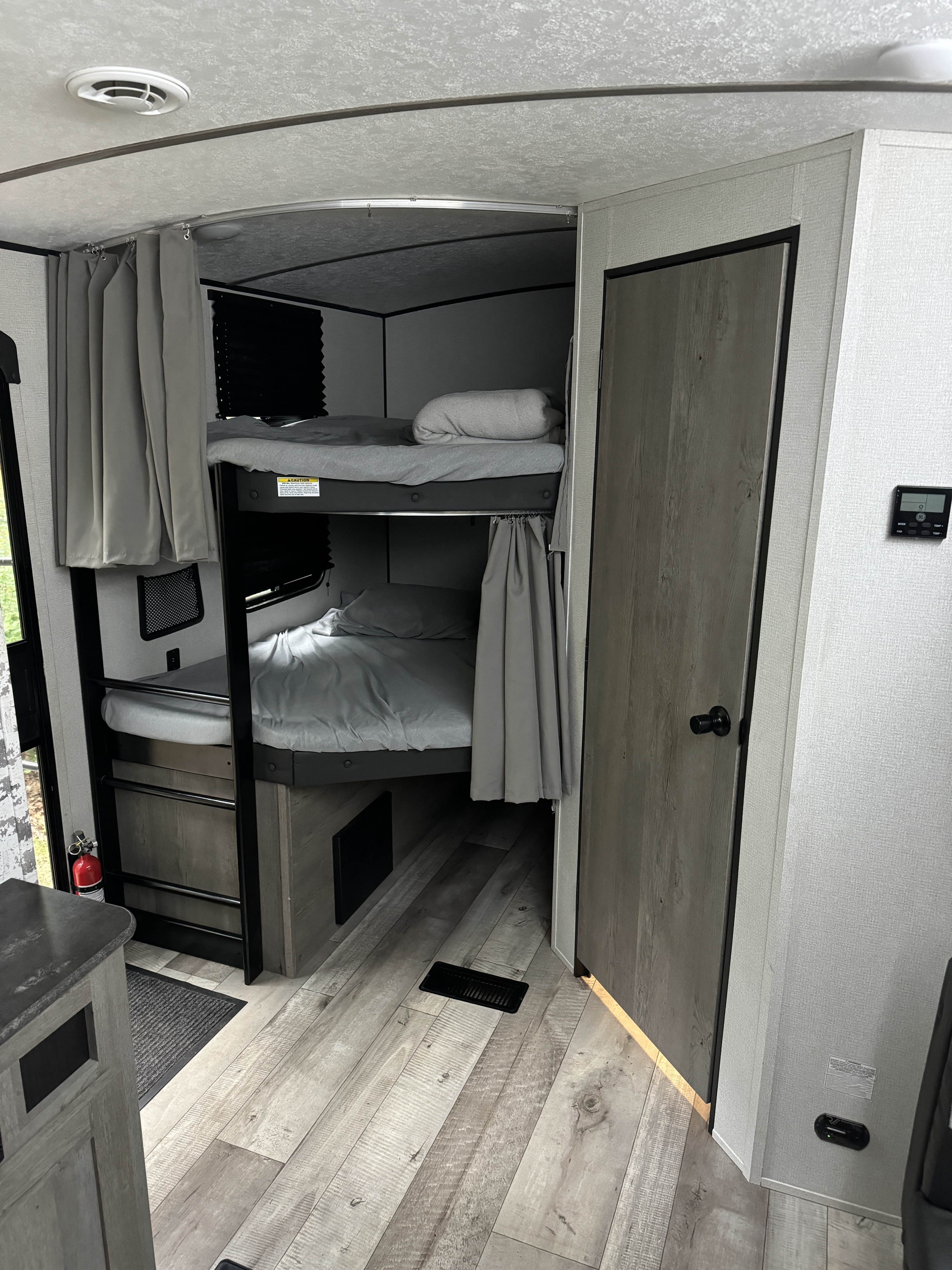 Inside an RV rental, showing the cozy bunk bed sleeping area with privacy curtains and ladder, designed for efficient use of space.. Keystone Springdale 2021