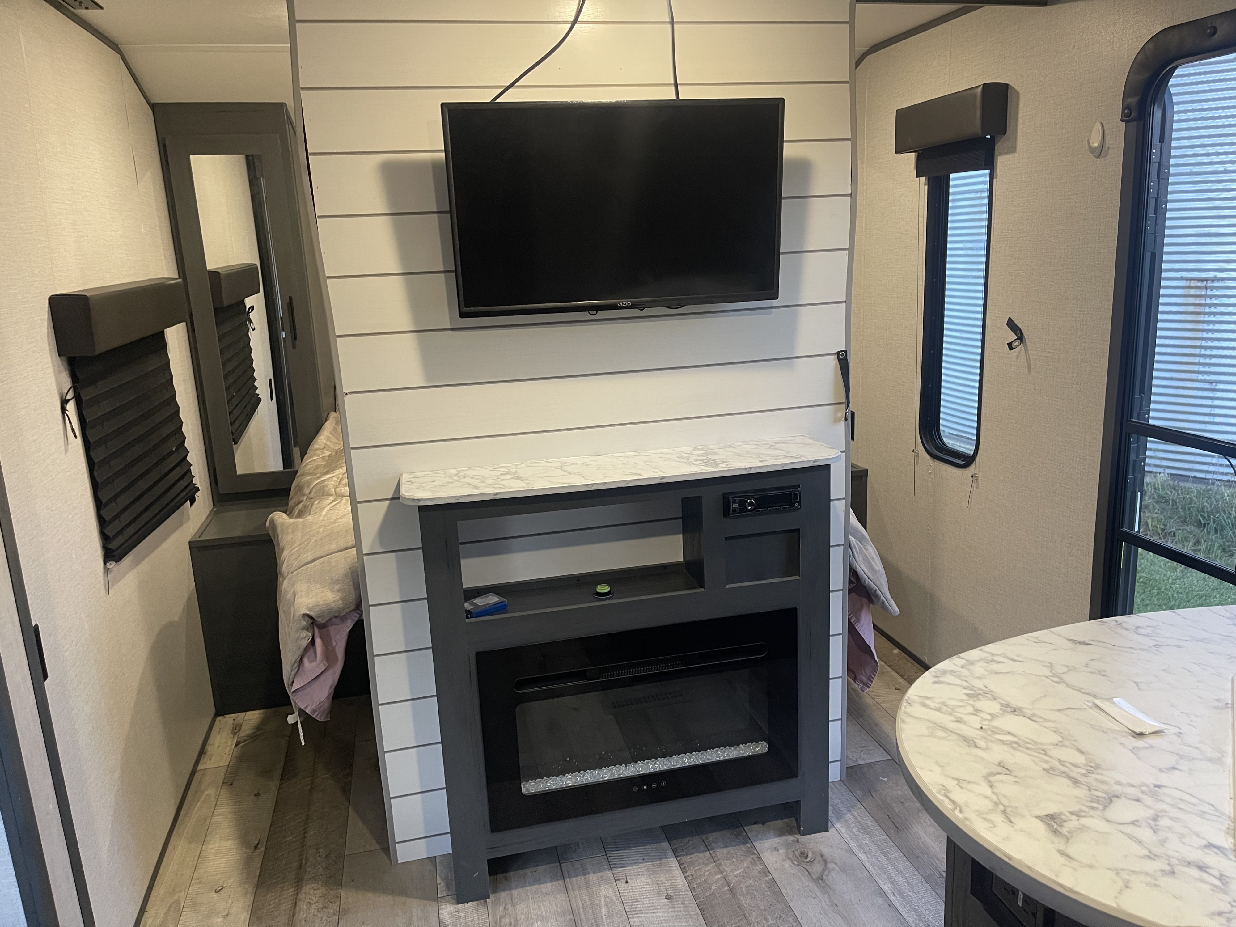 Cozy RV rental interior featuring a TV, electric fireplace, and dining area, ideal for comfortable travel adventures.. Dutchmen Aspen Trail 2021