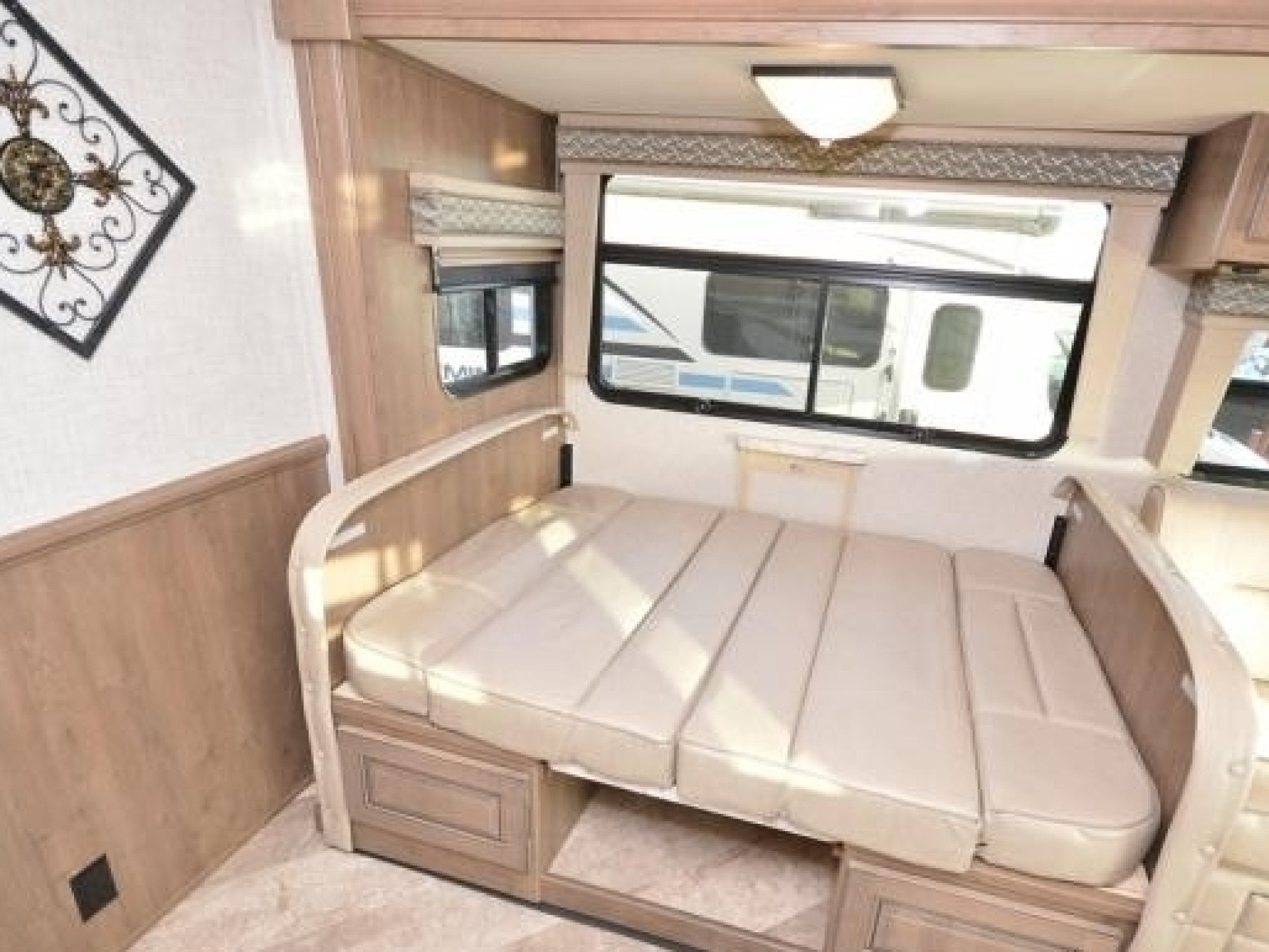 RV rental with a light-colored, convertible bed/couch against wood paneling and windows. A cozy, compact travel space.. Georgetown GT5 2019