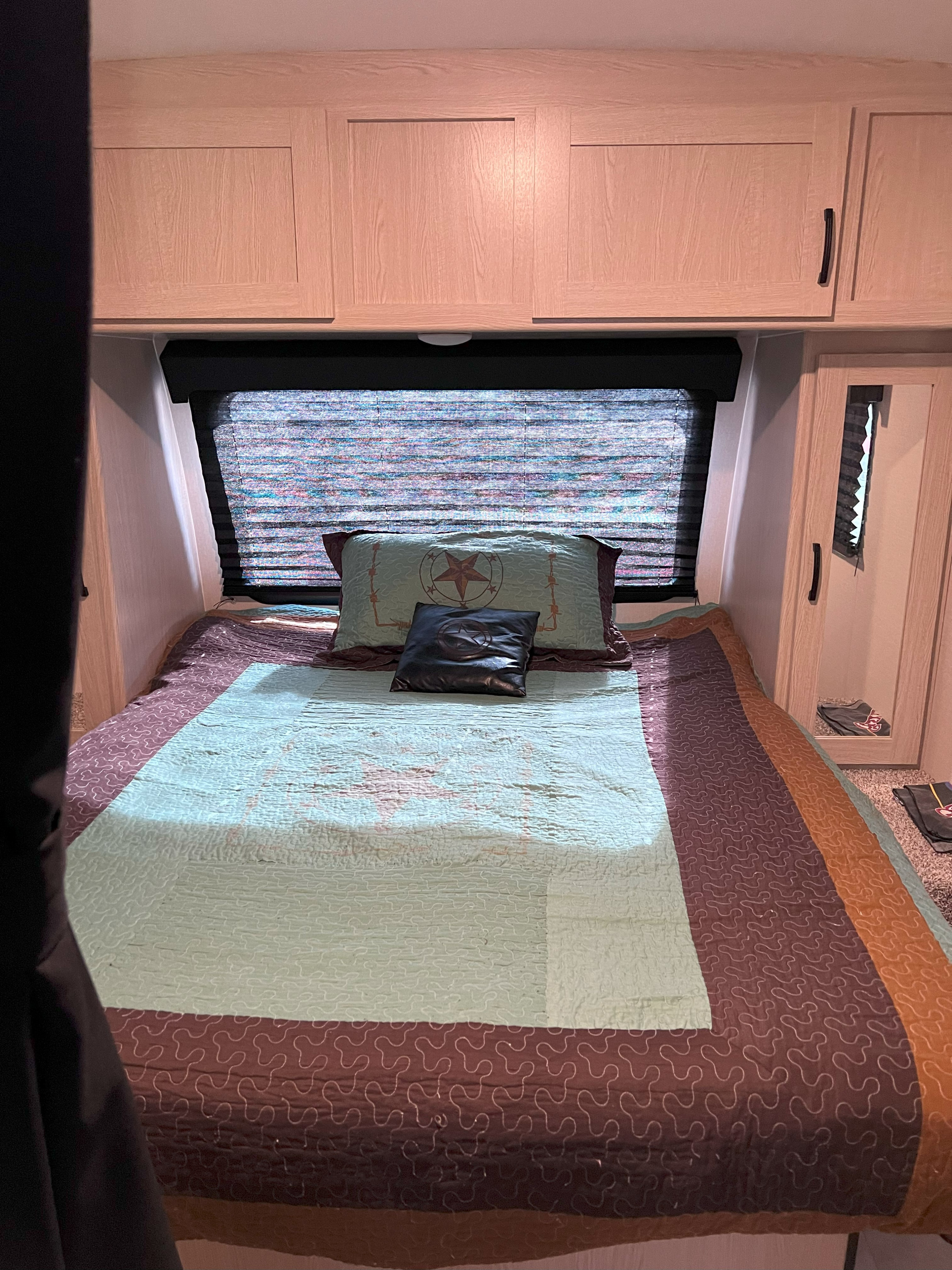 RV rental bedroom: a cozy bed with quilt & pillows, window blinds, and light wood overhead cabinets. Comfortable space.. Coachmen Apex Nano 2021