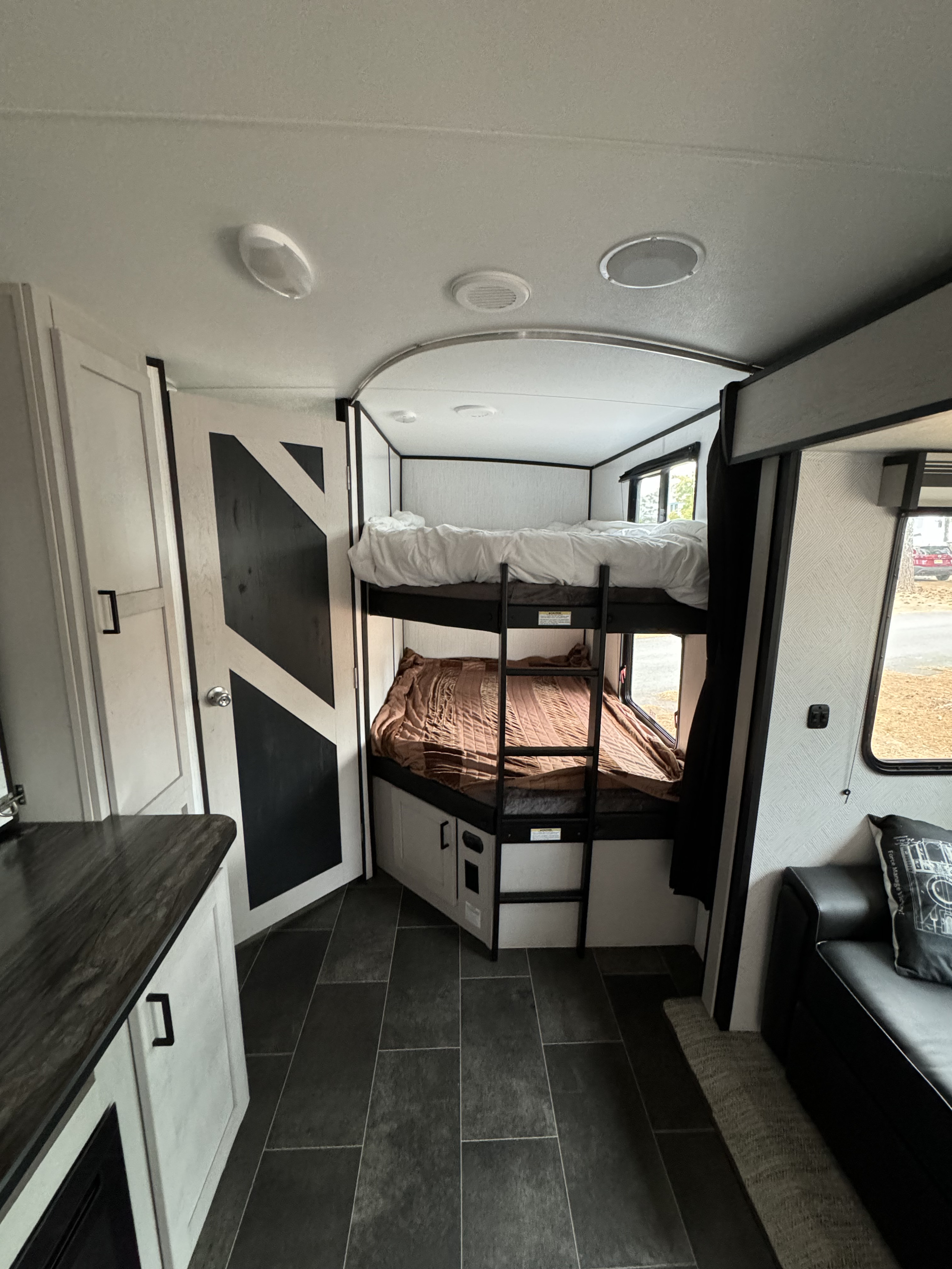 Modern RV rental interior with bunk beds, kitchen counter, and sofa, offering a functional and comfortable living space.. Heartland RVs Mallard 2022