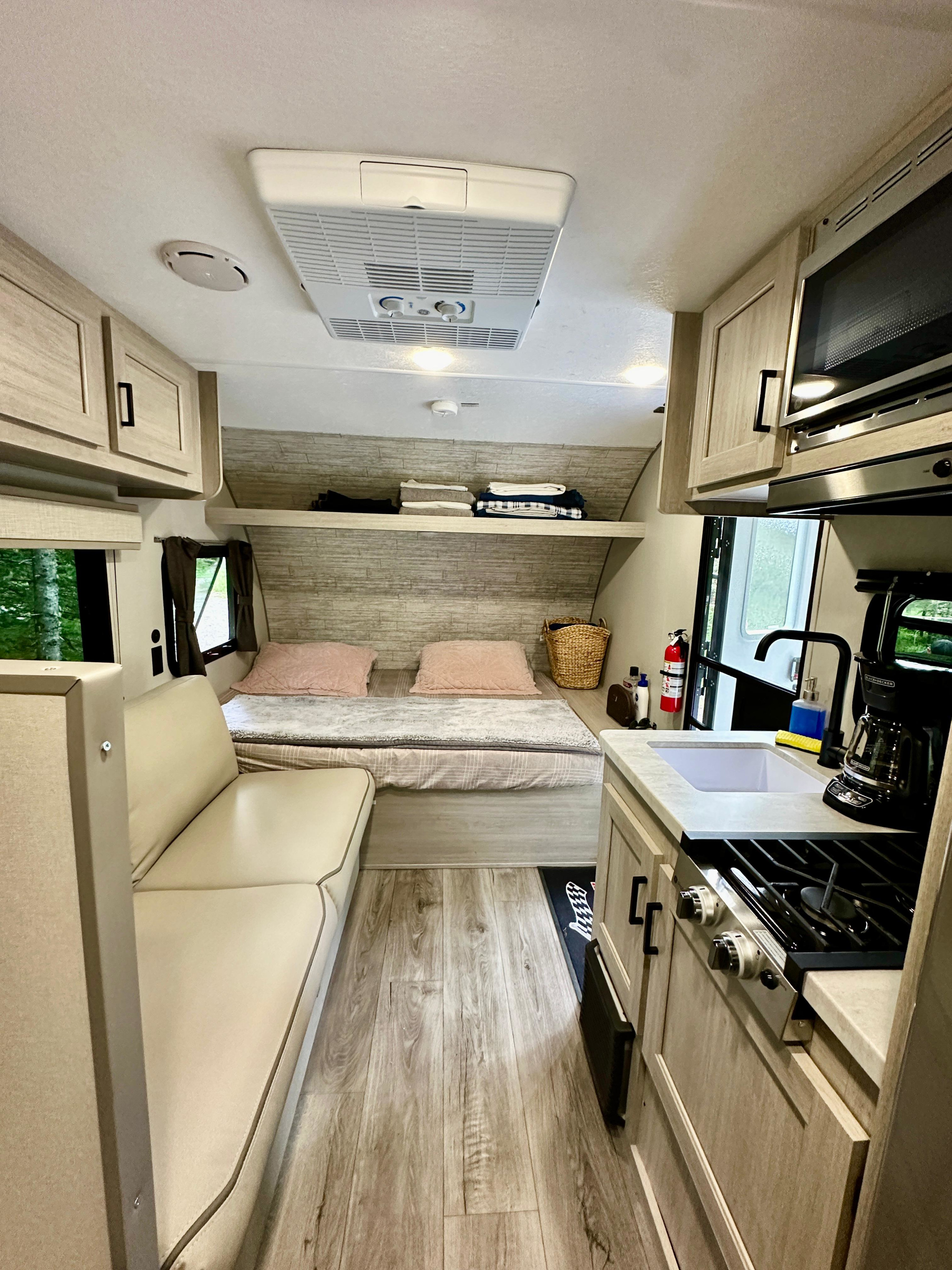 Spacious RV rental interior with a cozy bed, seating area, and full kitchen, perfect for travel. See compact living in this modern RV.. Coachmen 164 BHX 2024