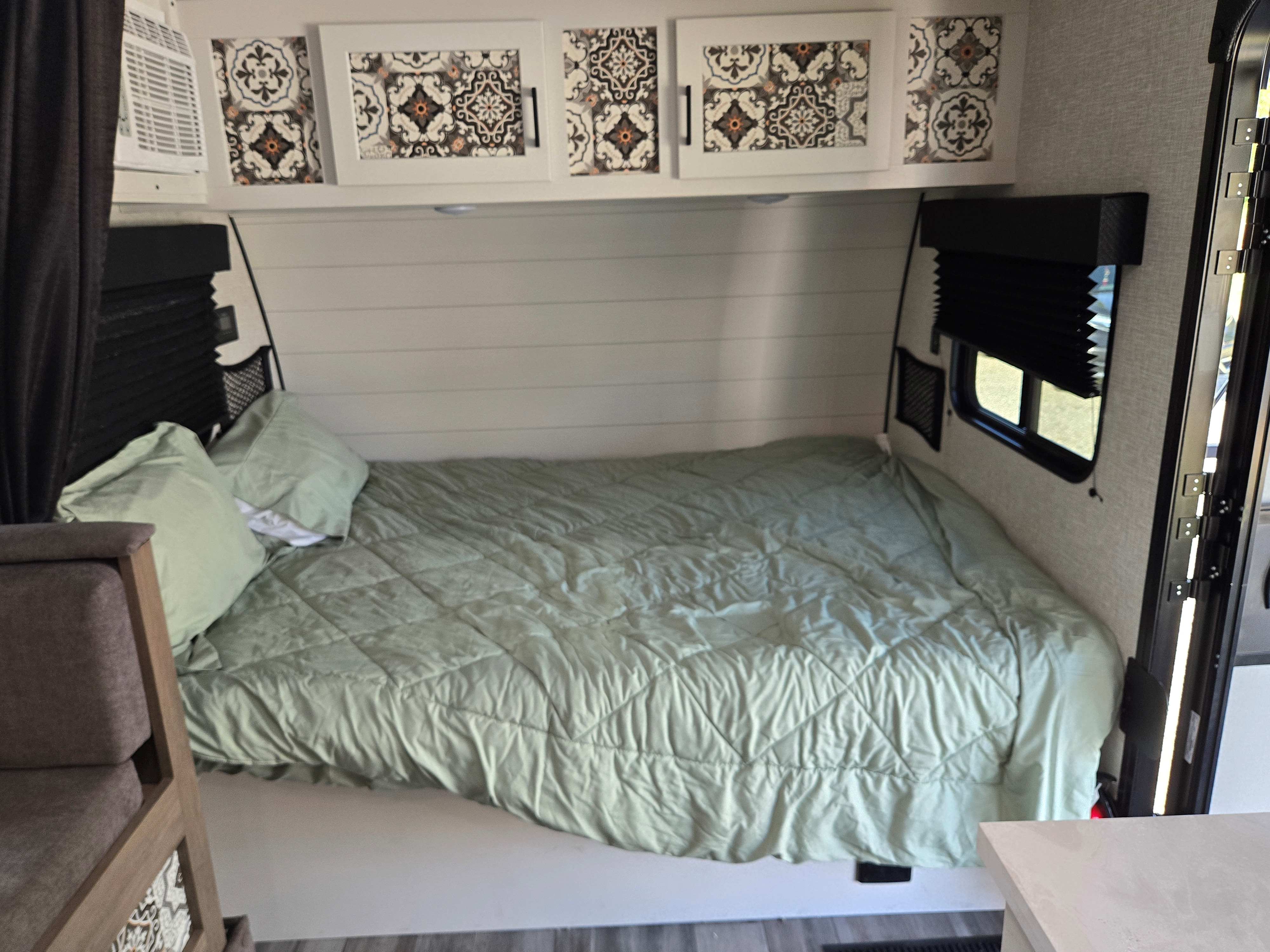RV rental interior: comfy bed with green bedding, unique patterned cabinets, window, and wall AC unit. Great for trips!. Jayco Jay Flight SLX 2024