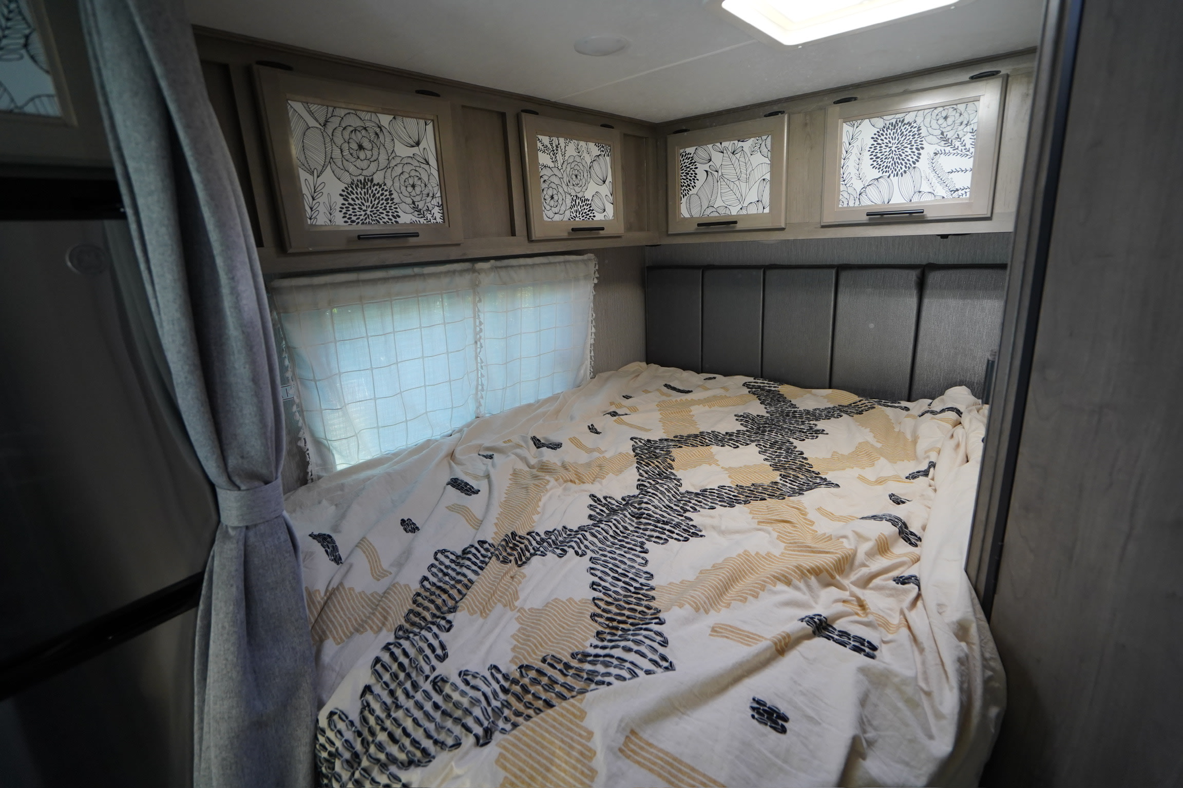 Cozy RV rental bedroom with patterned bedspread and floral overhead cabinets for comfortable travels.. Coachmen Cross Trail 2022