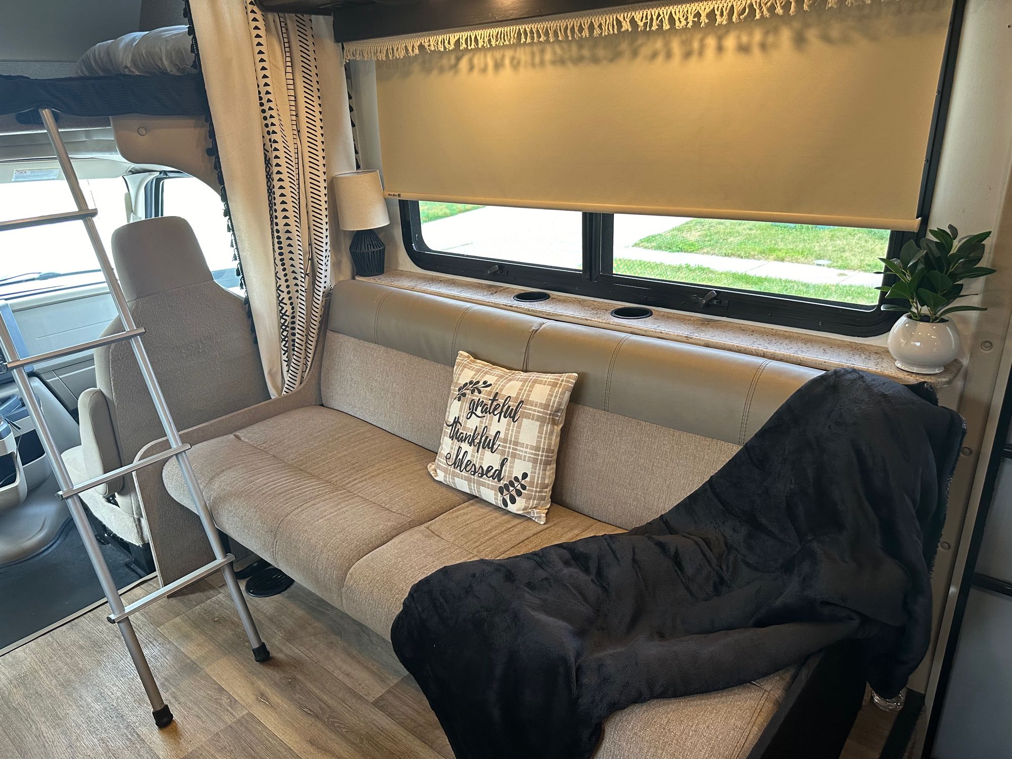 Warm RV rental living space featuring a sofa, decor, window, and bunk bed ladder for comfort.. Thor Four Winds 2017