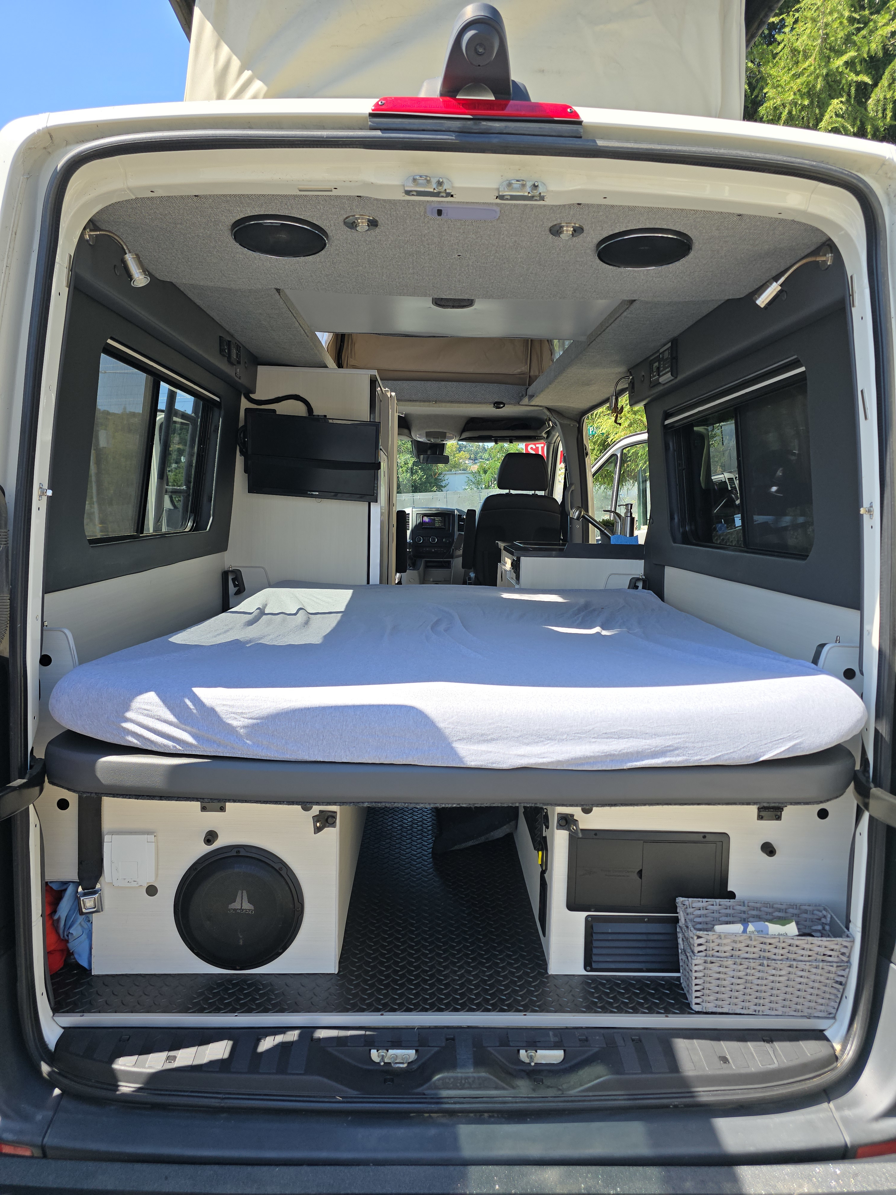 Spacious RV rental interior featuring a cozy bed, under-bed storage with subwoofer, and custom finishes for comfortable travel.. Sportsmobile Regular Body 4X4 2017