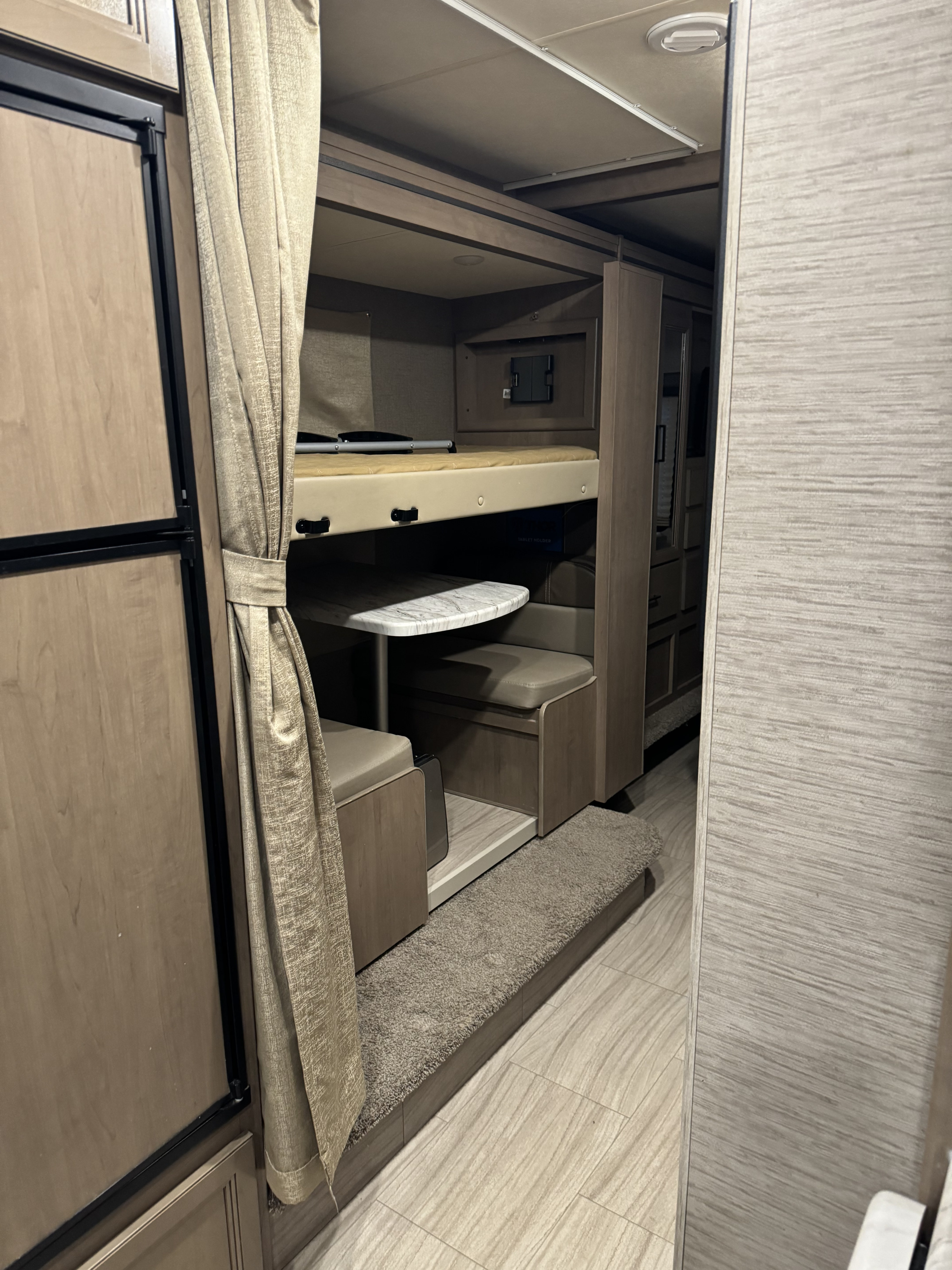RV rental showing a compact interior with a refrigerator, bunk bed, and a convertible dinette. Perfect for your camper travels.. Thor Coleman 2021