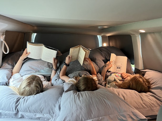 RV rental travel: Three children reading books comfortably in their camper bed.. Volkswagen California Beach Camper 2024