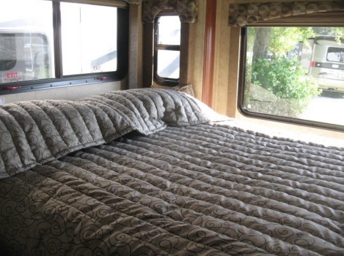 Enjoy the comfort of an RV rental: a cozy bedroom with quilted bedding and scenic window views.. Forester Forester Motorhome 2012