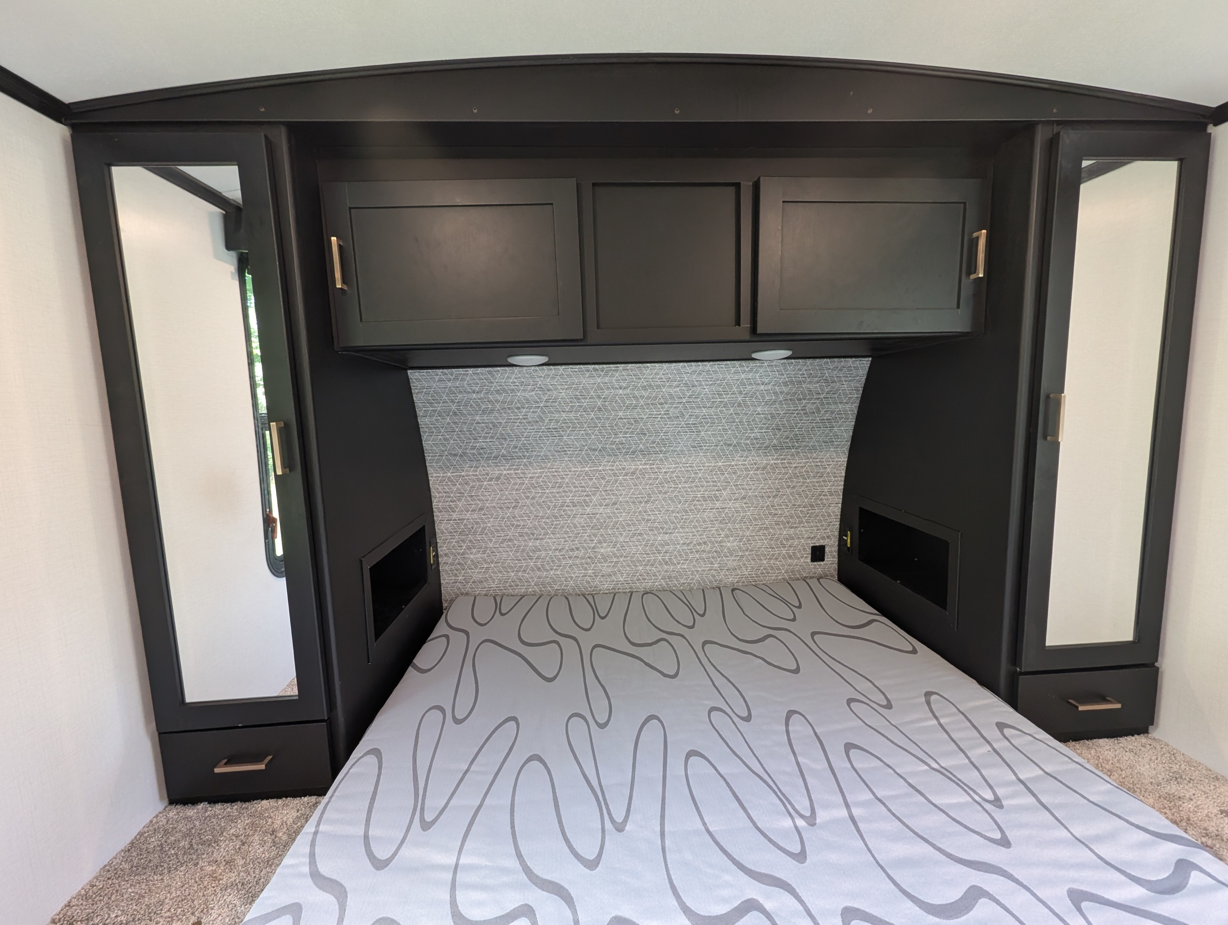 RV rental bedroom with a bed, dark modern cabinetry, and integrated lighting.. Keystone RV Outback 2022