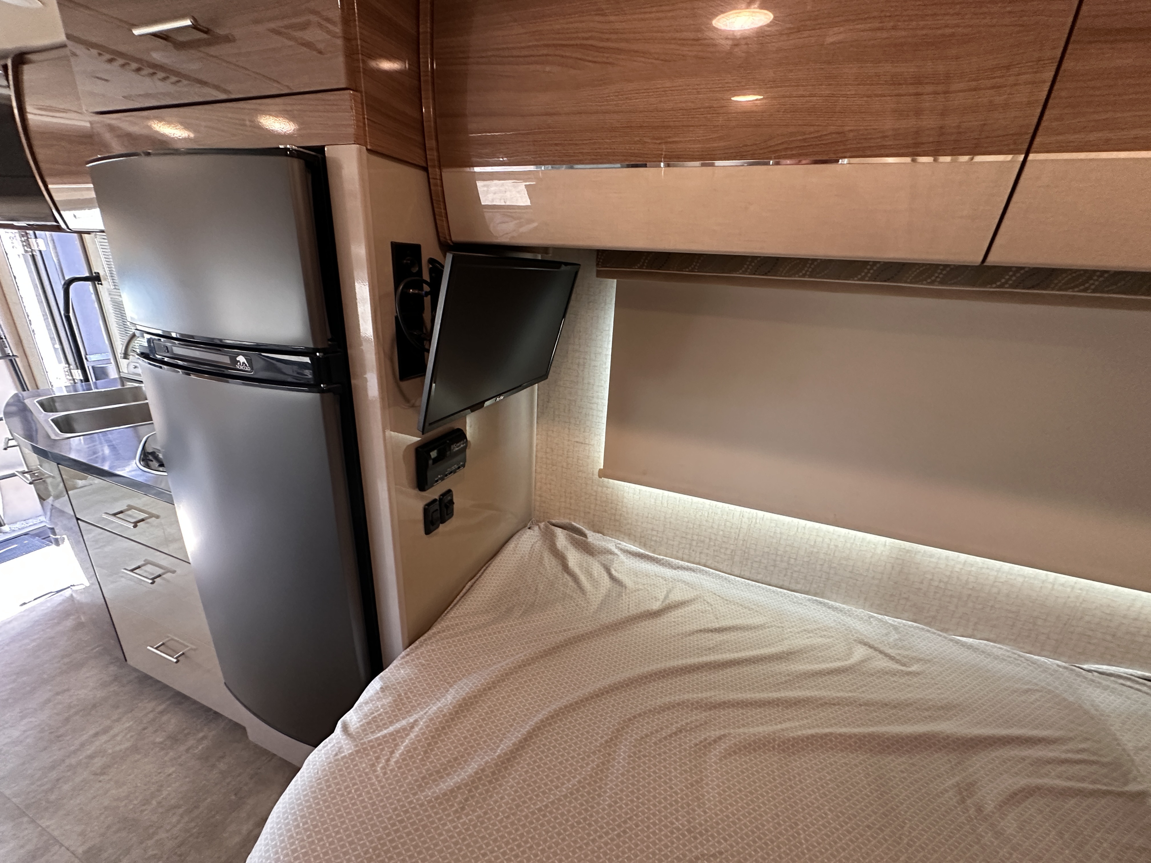 Modern RV rental interior: Compact kitchen, fridge, TV, & cozy bed. Perfect for travel.. Winnebago View 2016
