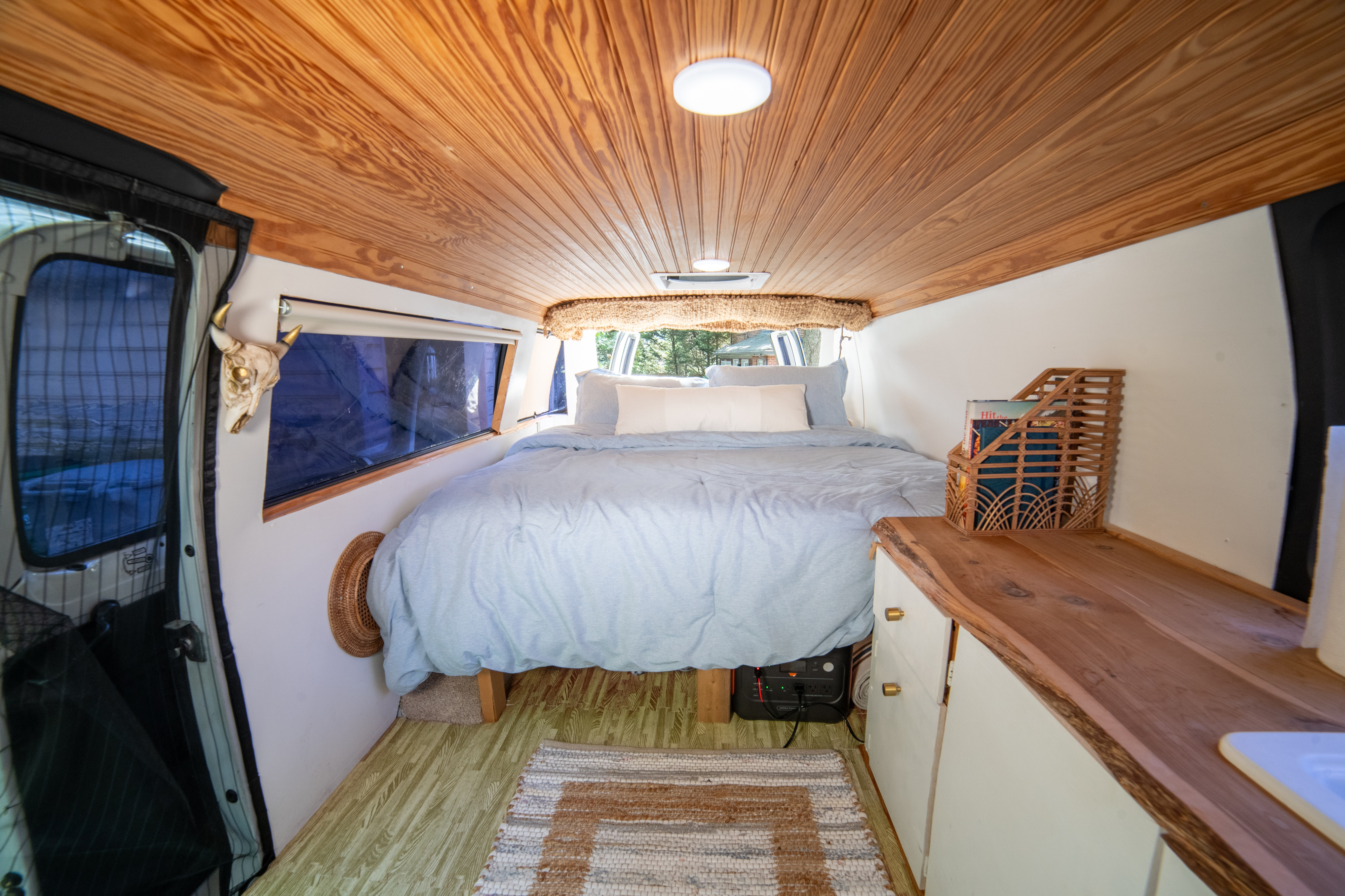 Cozy rv rental interior with a light blue bed, wooden ceiling, and ample storage, perfect for a comfortable road trip.. Dodge 1500 2001