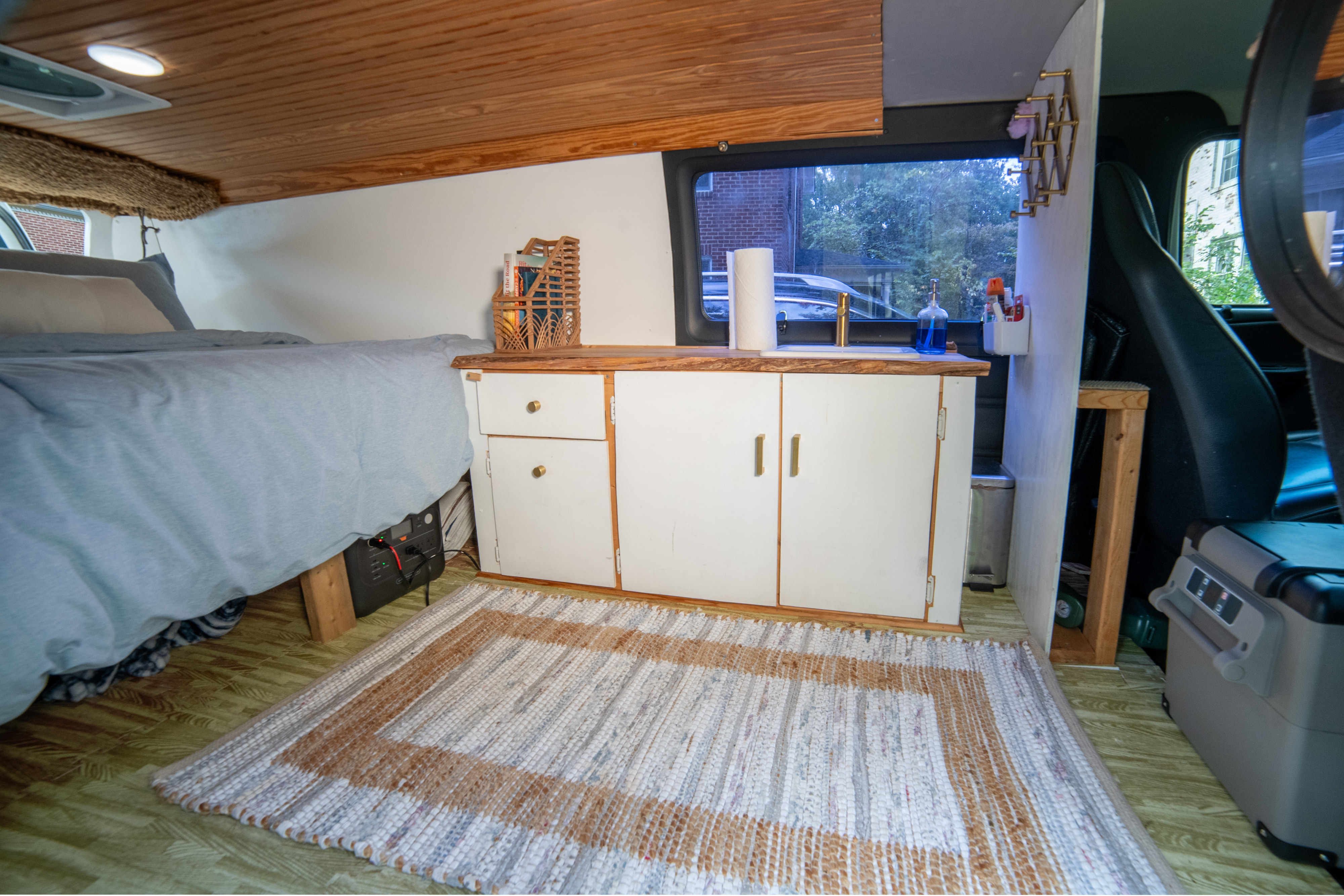 Custom RV rental interior: a cozy bed, compact kitchen with sink, and cabinet storage, perfect for mobile living.. Dodge 1500 2001