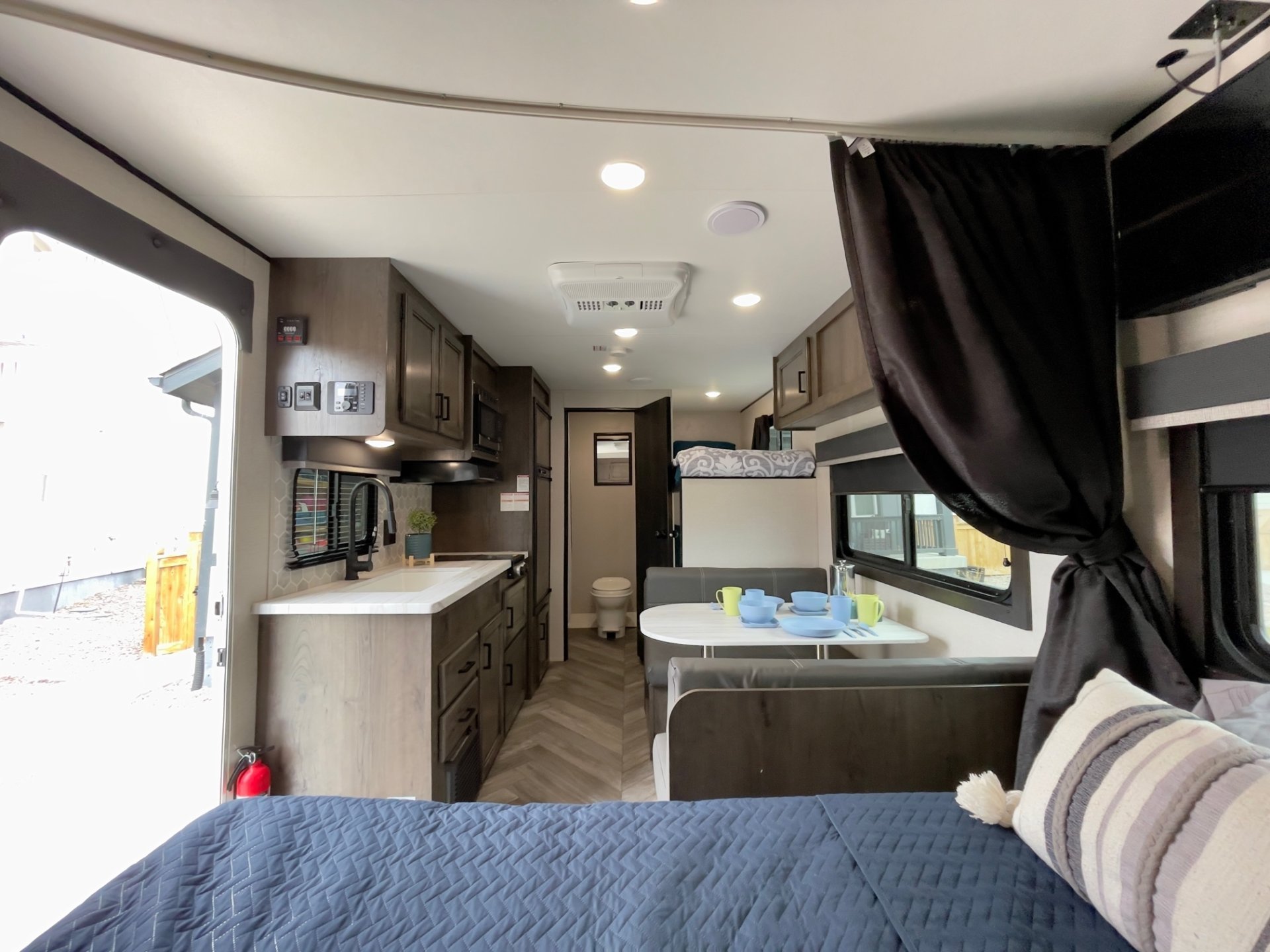 Modern RV rental interior with kitchenette, dinette, bunk beds, and a front bedroom featuring a blue quilted bedspread.. Highland Ridge Olympia Sport 2022