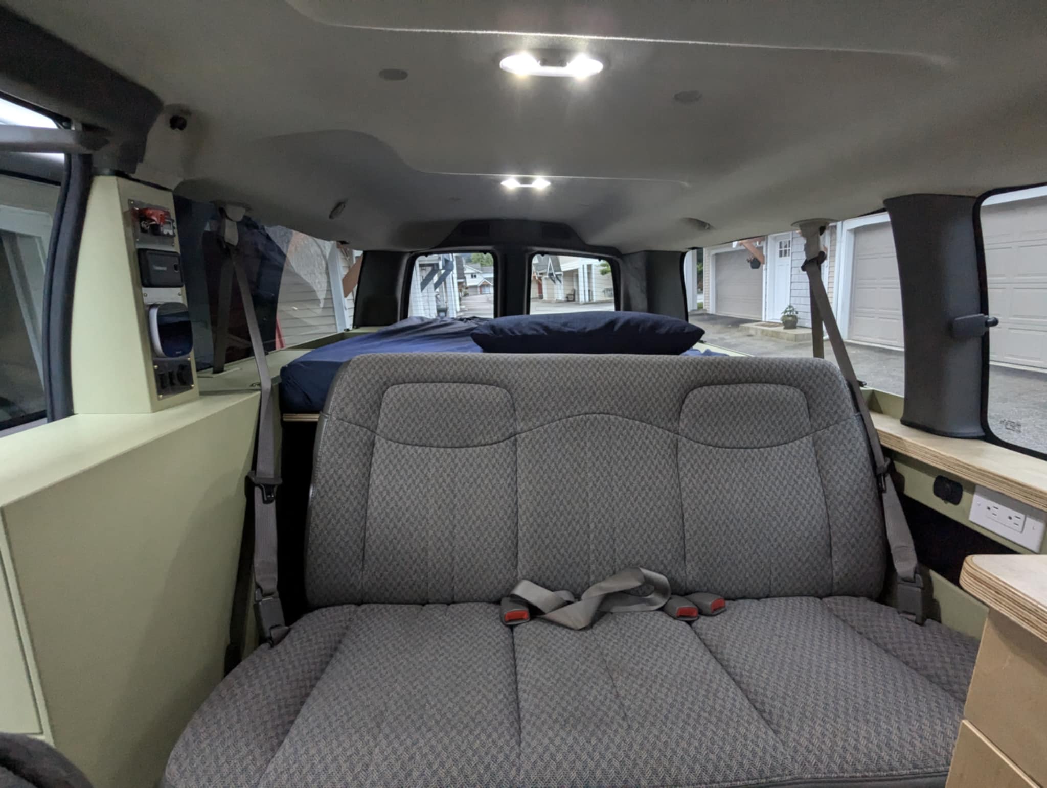 Spacious custom van conversion interior with rear seating, a comfy bed, and handy power outlets, ideal for RV rental.. Chevrolet Express 3500 2007