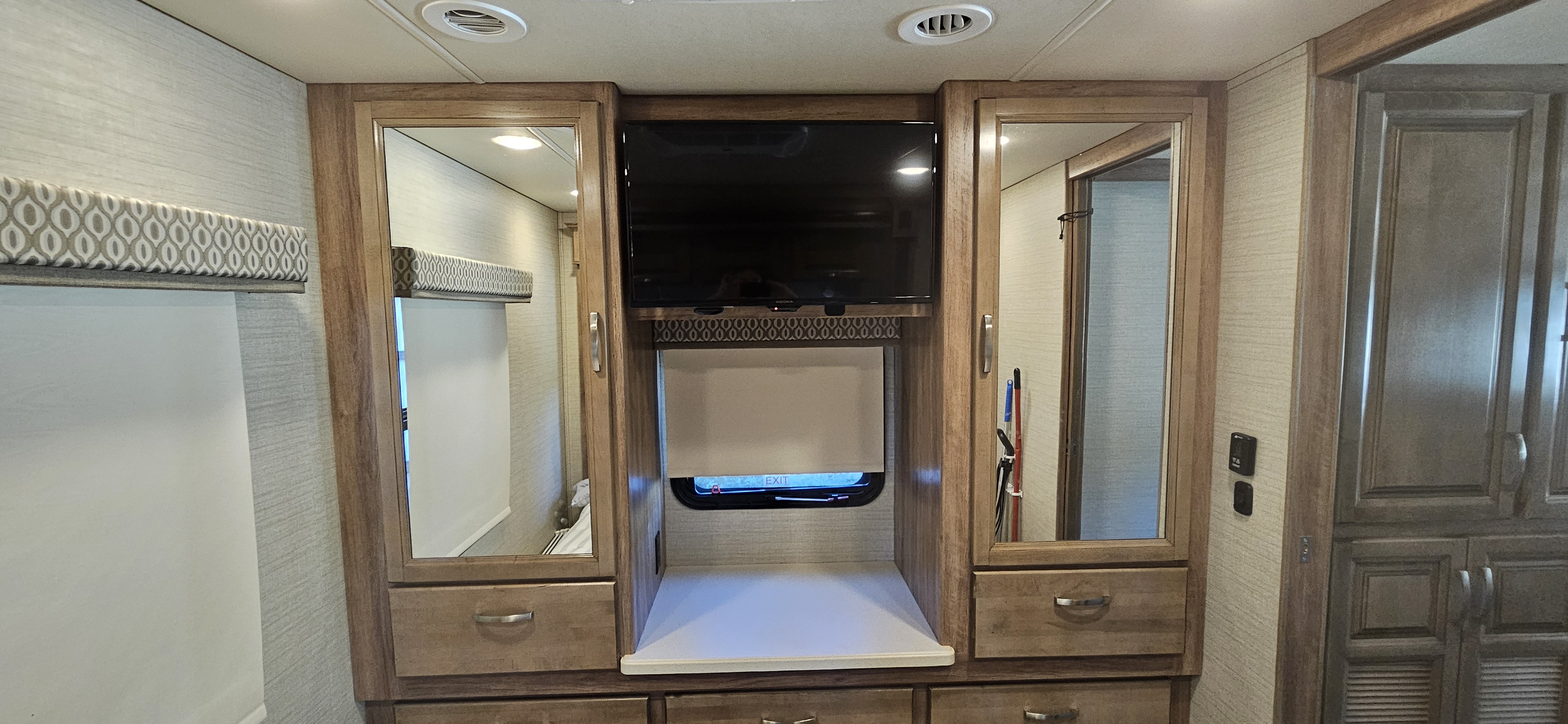 RV rental motorhome interior: bedroom area with TV, mirrored wardrobes, and abundant wooden cabinetry.. Jayco Precept 2019