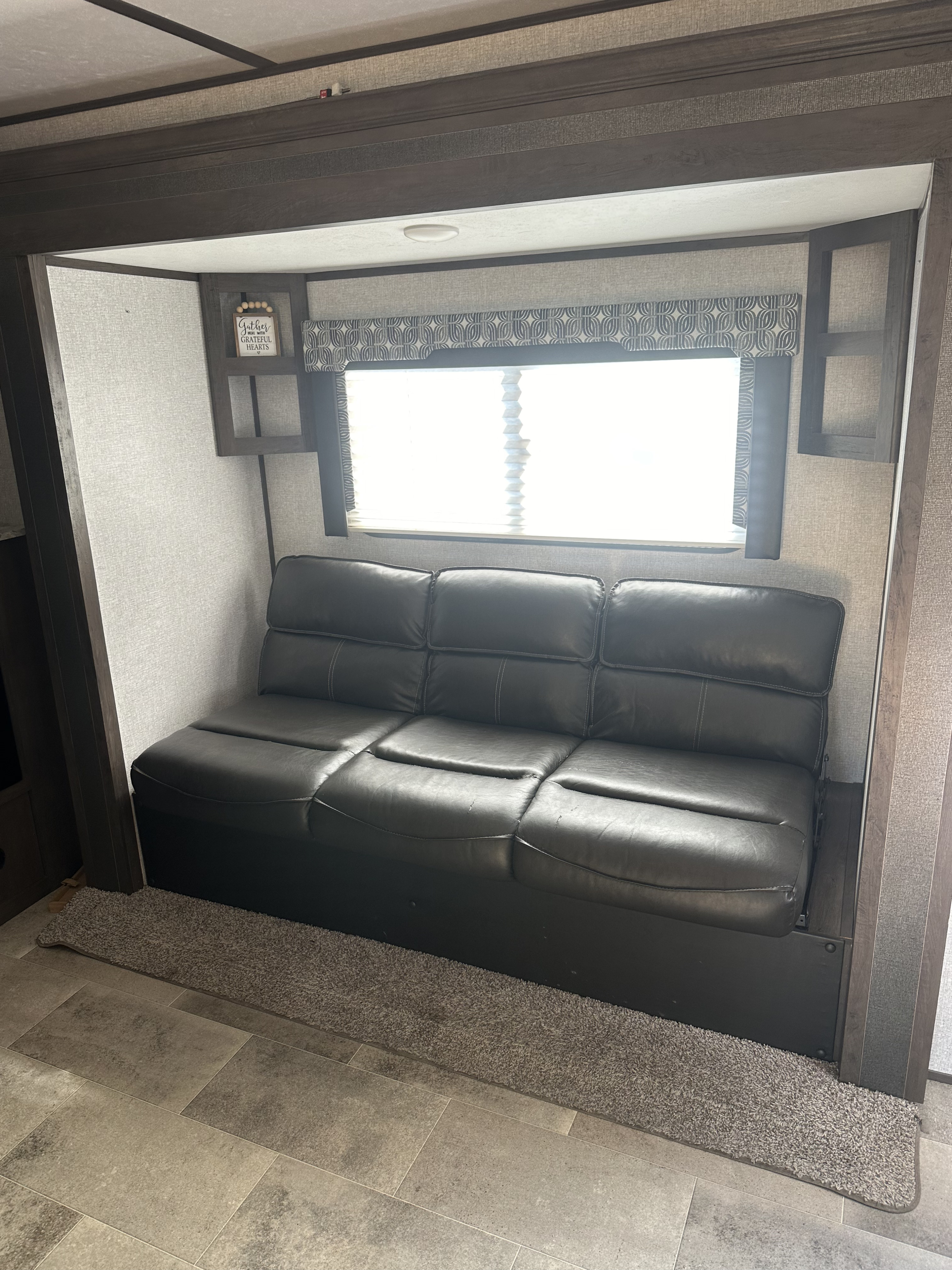 Spacious RV rental living area featuring a comfy black sofa/bed and modern decor.. Dutchmen Coleman Light 2020