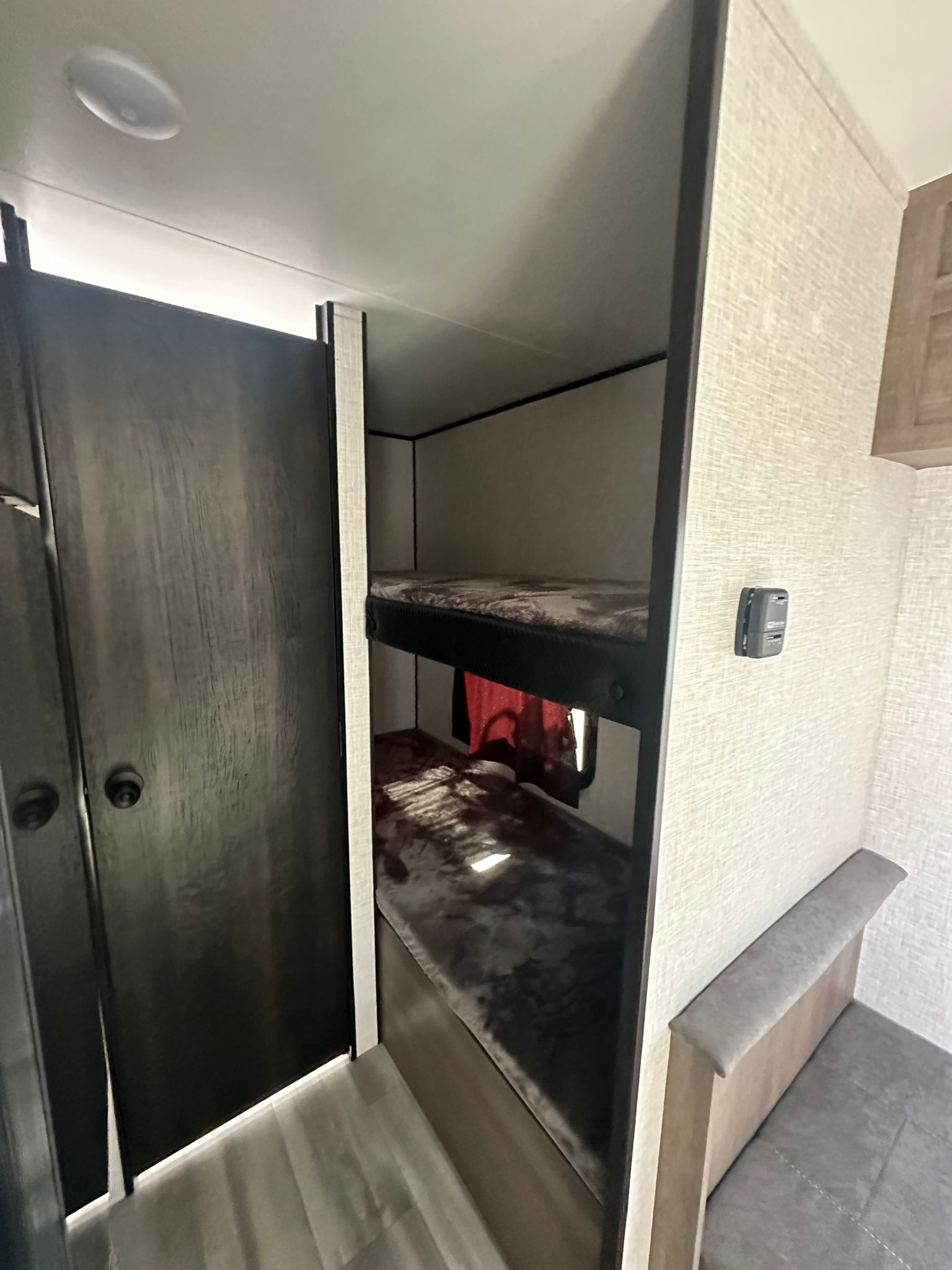 RV rental interior: two dark bunk beds, a light gray dinette, and a door, designed for a comfortable camper stay.. Jayco Jay Flight SLX 2024