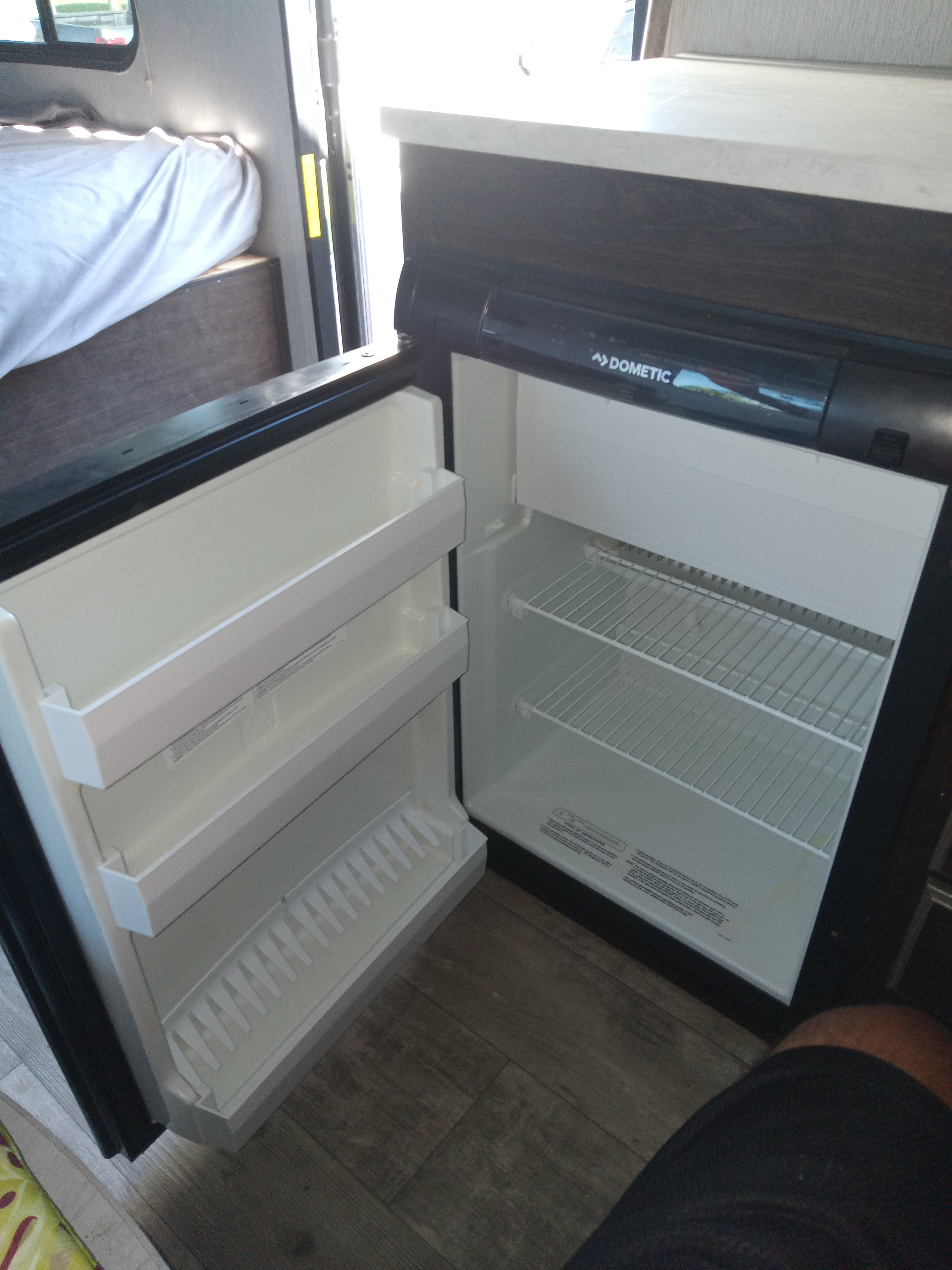 RV rental: The interior shows an open Dometic refrigerator with shelves. A bed is visible in the background of this camper.. Pioneer Trail Blazer 2020