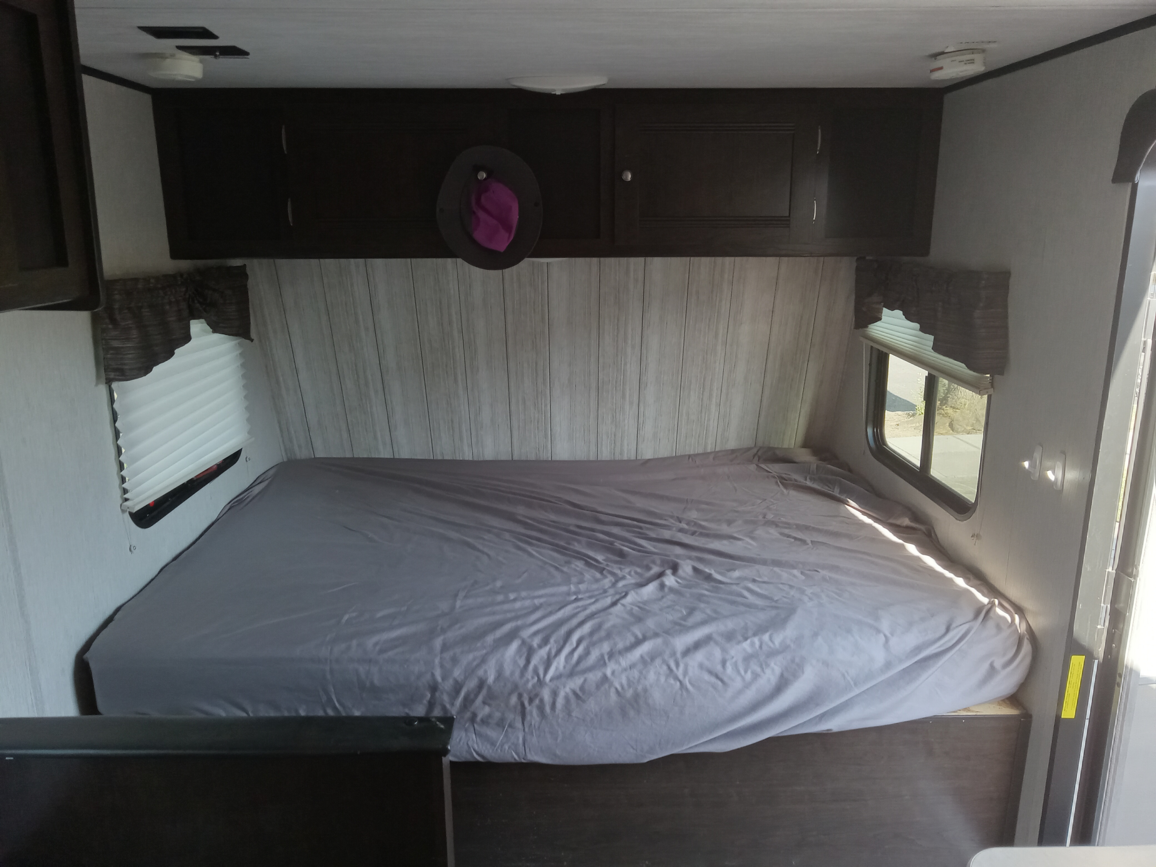 Experience comfort in this RV rental bedroom: a spacious bed, overhead storage, and windows with shades.. Pioneer Trail Blazer 2020