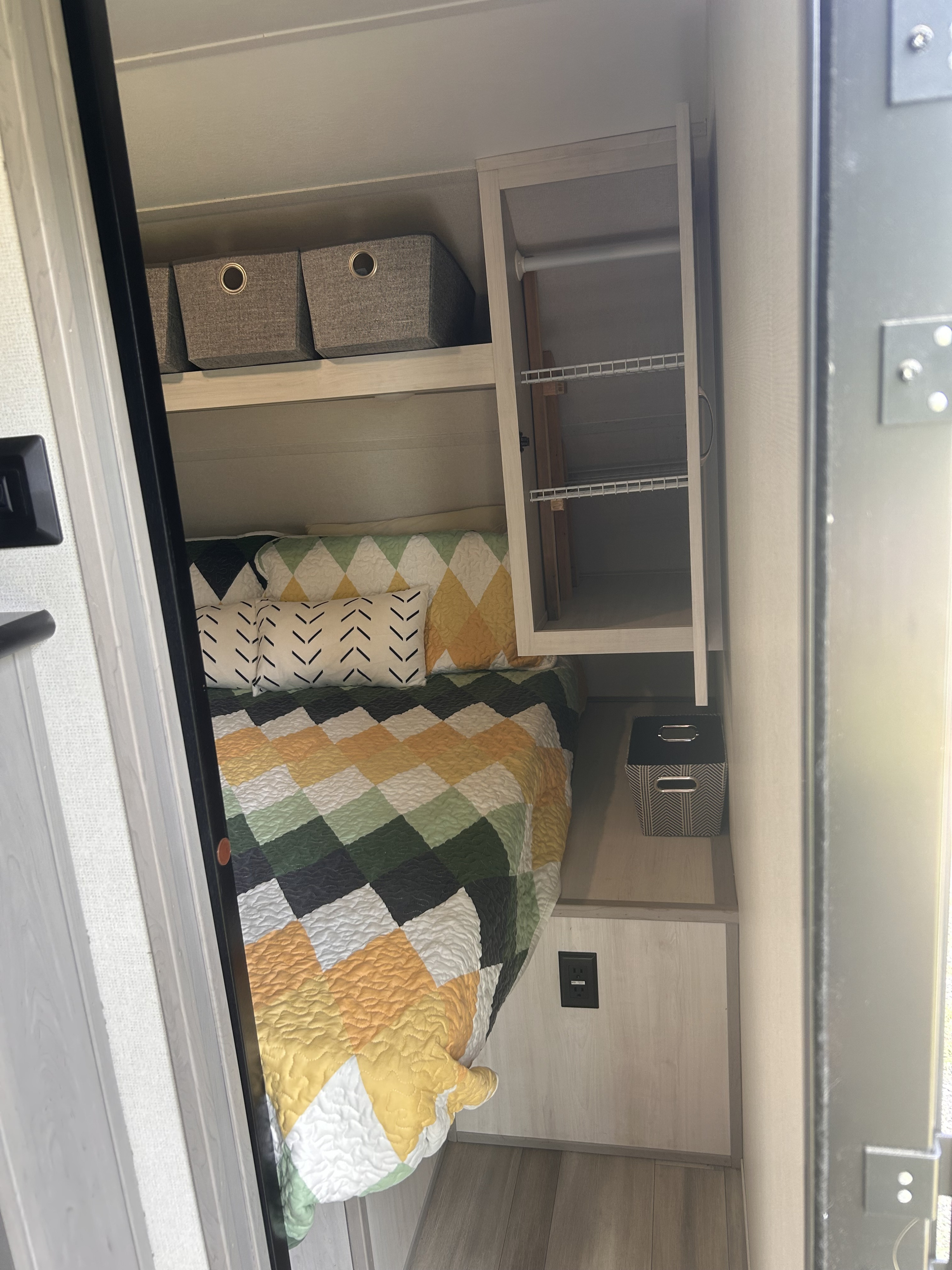 RV rental: compact bedroom featuring a patterned quilt, overhead storage bins, and a built-in closet.. Forest River Tracer LE 2022
