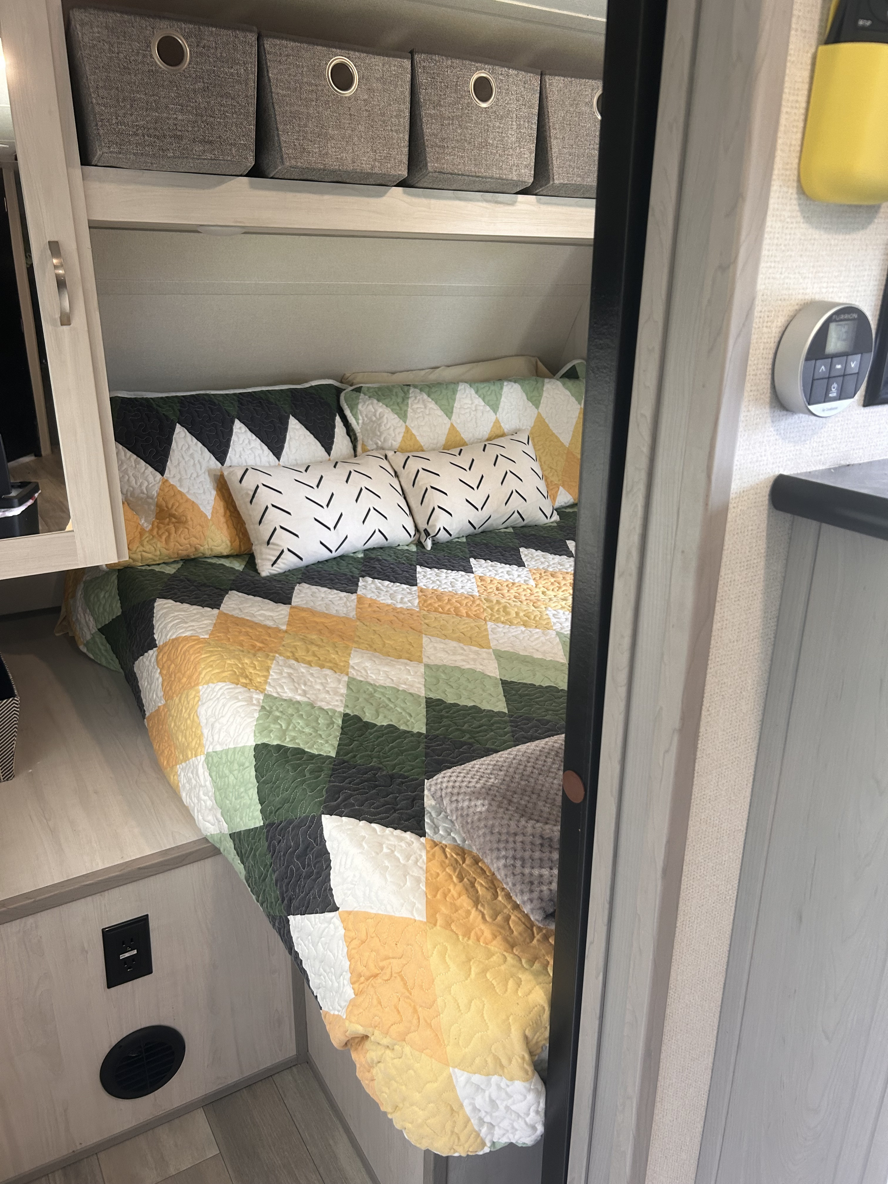 Cozy RV rental bedroom featuring a geometric quilt, storage bins, and climate control for a comfortable stay.. Forest River Tracer LE 2022