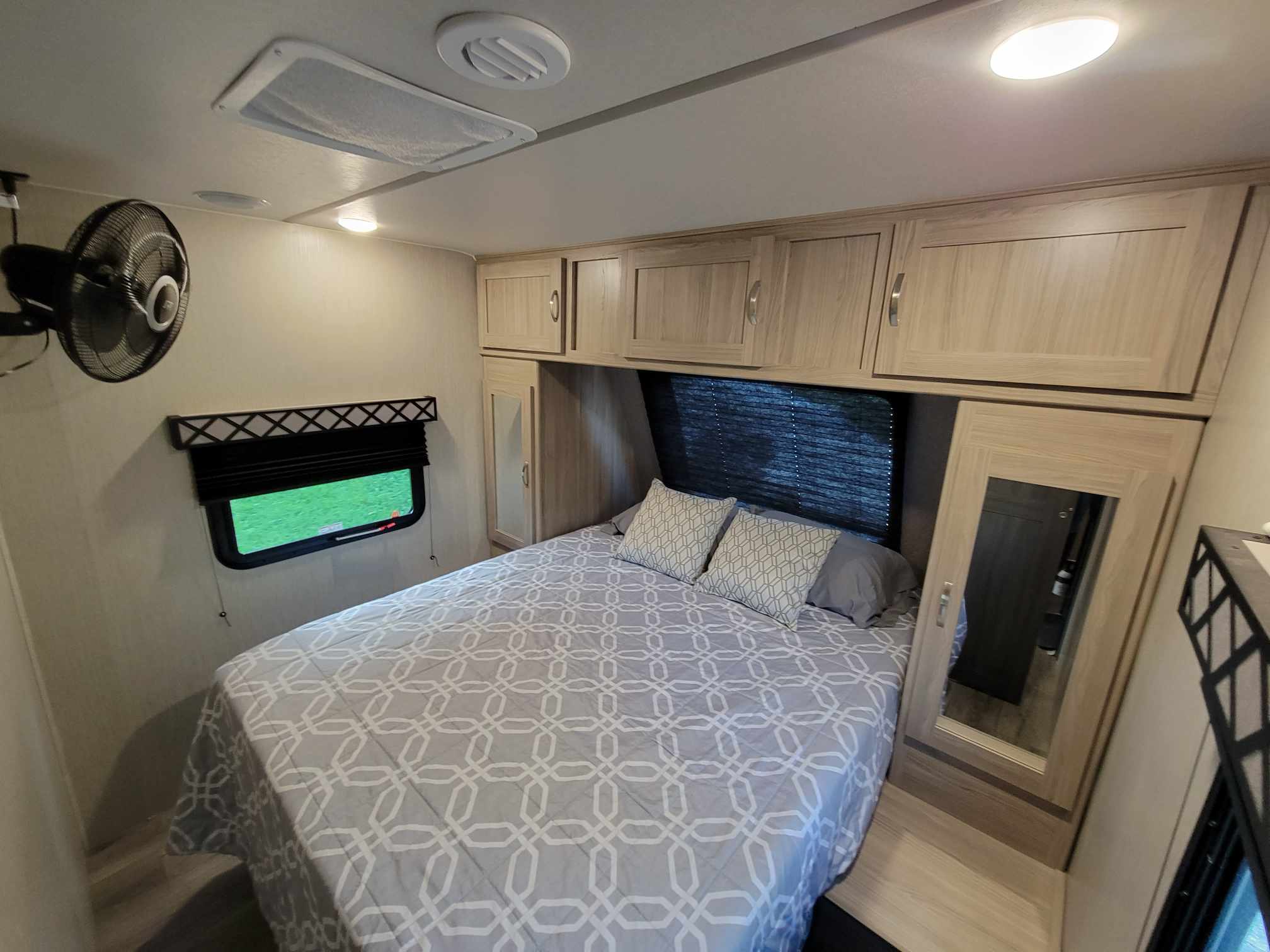 Comfortable RV rental bedroom featuring a queen bed, overhead cabinets, wall fan, and window. Perfect for your travels.. Coachmen Freedom Express 248RBS 2020