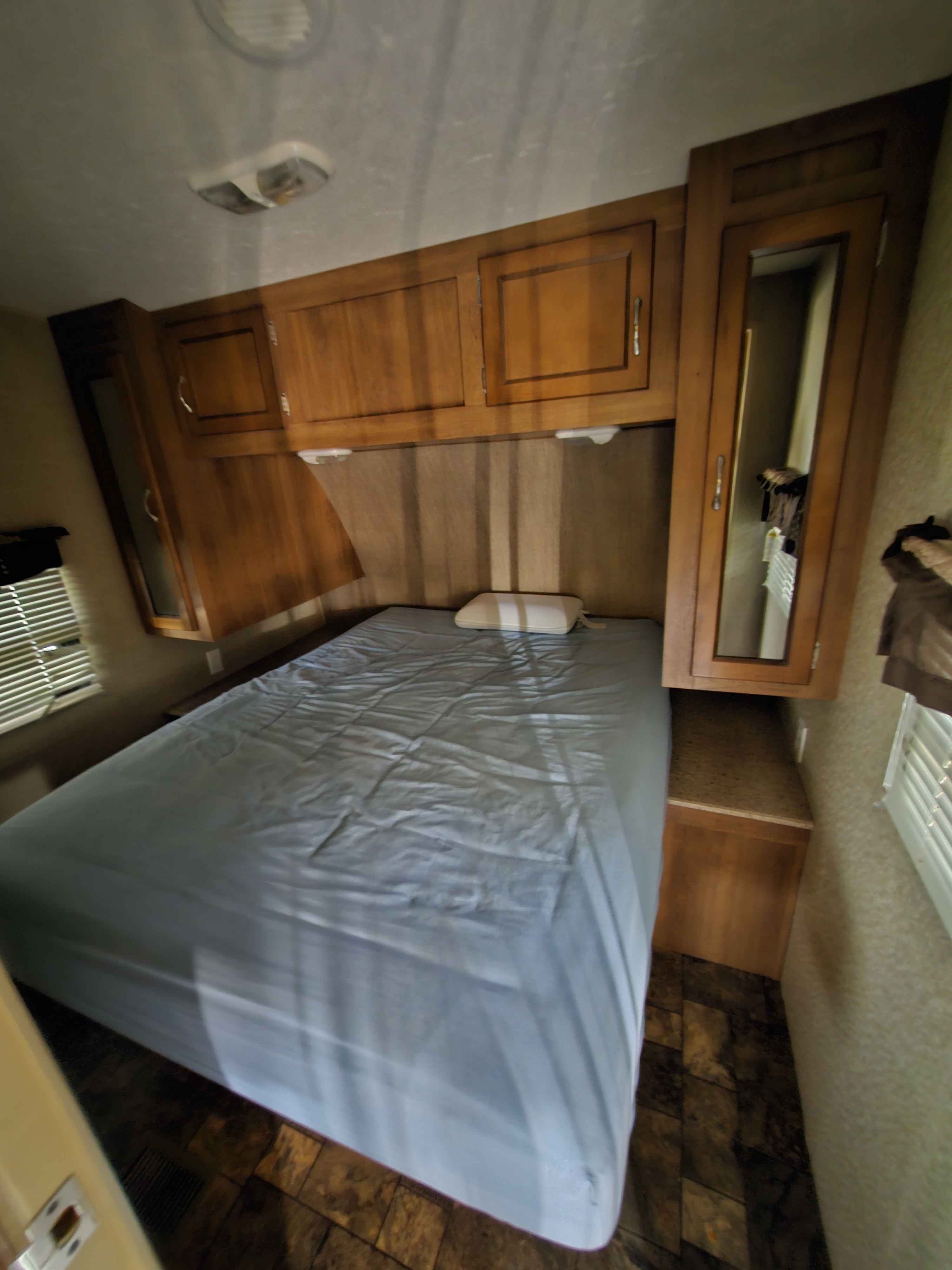 RV rental bedroom: cozy sleeping area with wooden cabinets, mirrored closet, and bed with blue sheet.. Forest River Coachmen Catalina 2015