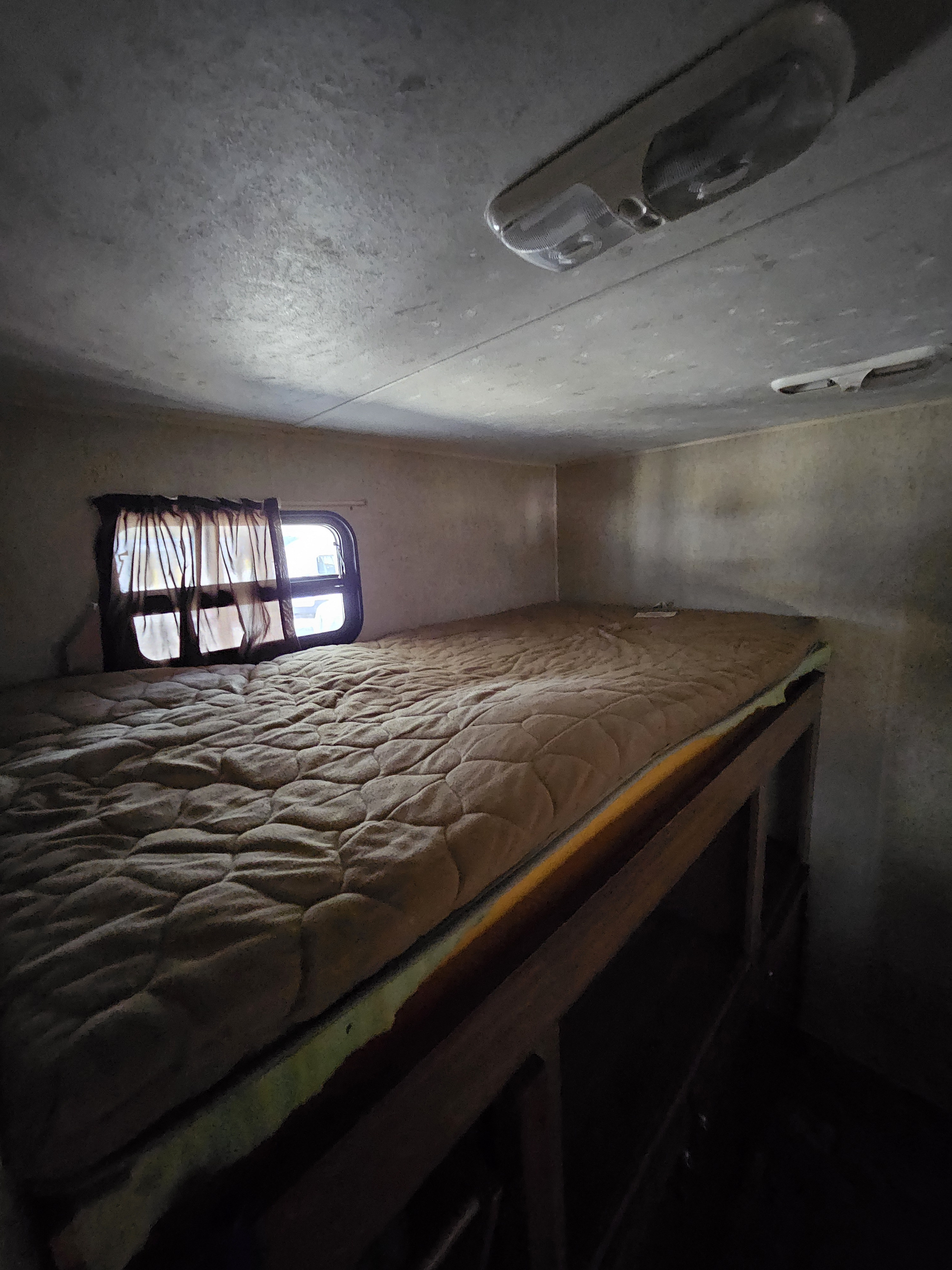 Inside an RV rental: a compact bunk bed with a quilted mattress, window, and ceiling light for. Forest River Coachmen Catalina 2015