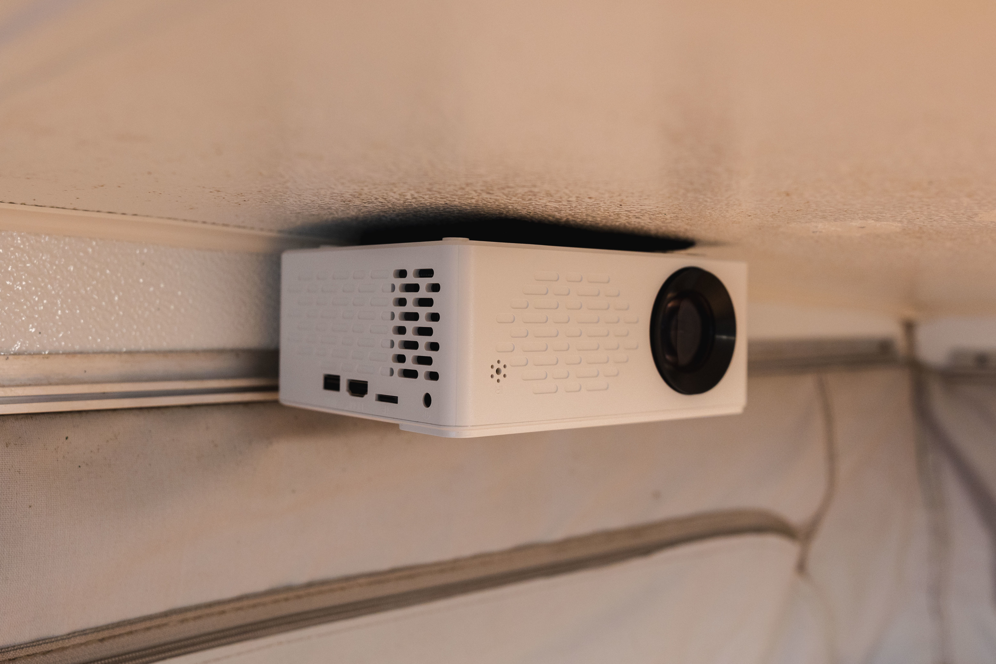 A small white projector, ceiling-mounted in an RV rental, offers on-the-go entertainment.. Starcraft Sportstar 1991