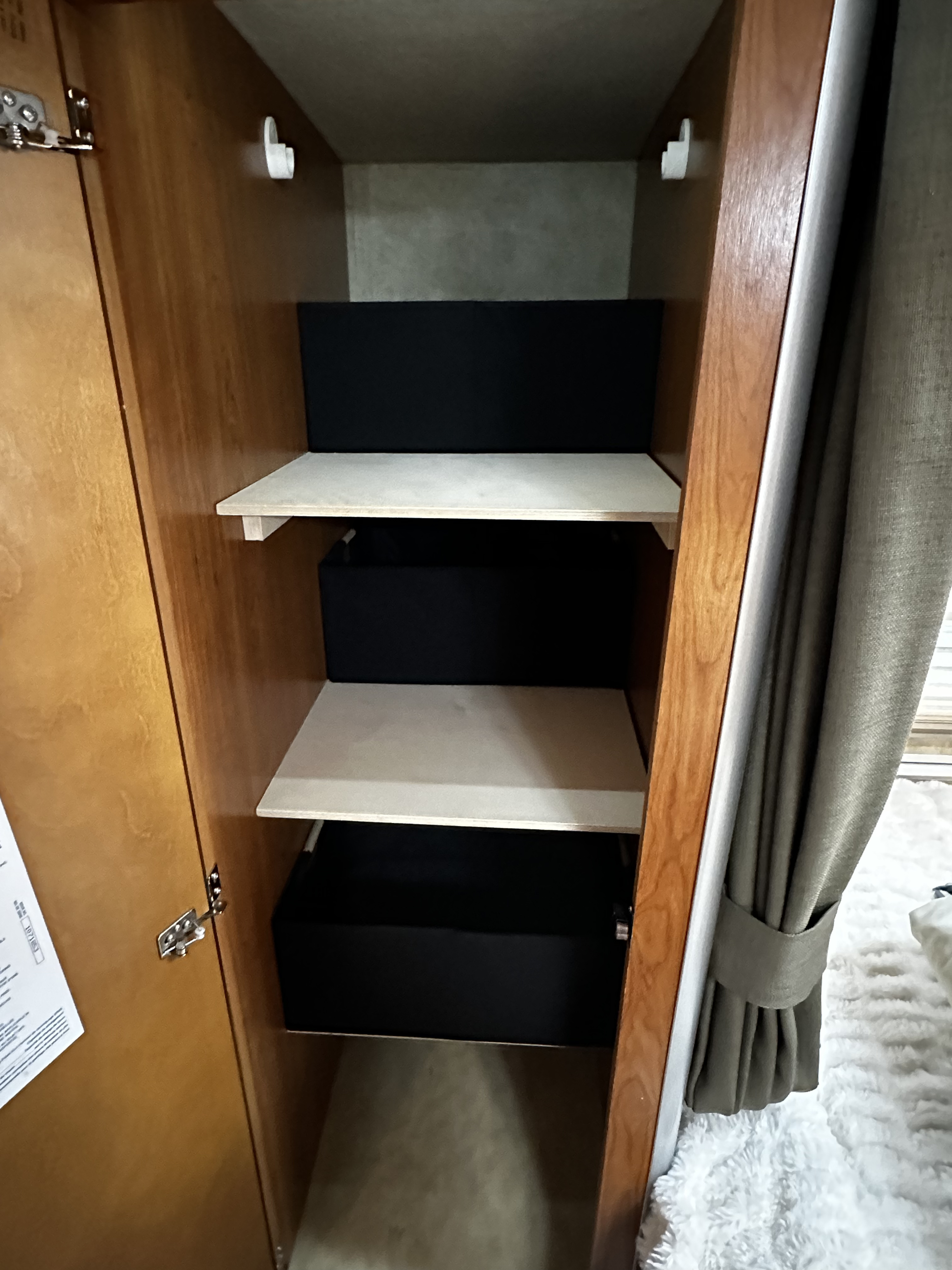 RV rental storage: Organized RV cabinet with light shelves and black bins. Perfect for compact living.. Winnebago Itasca 2007