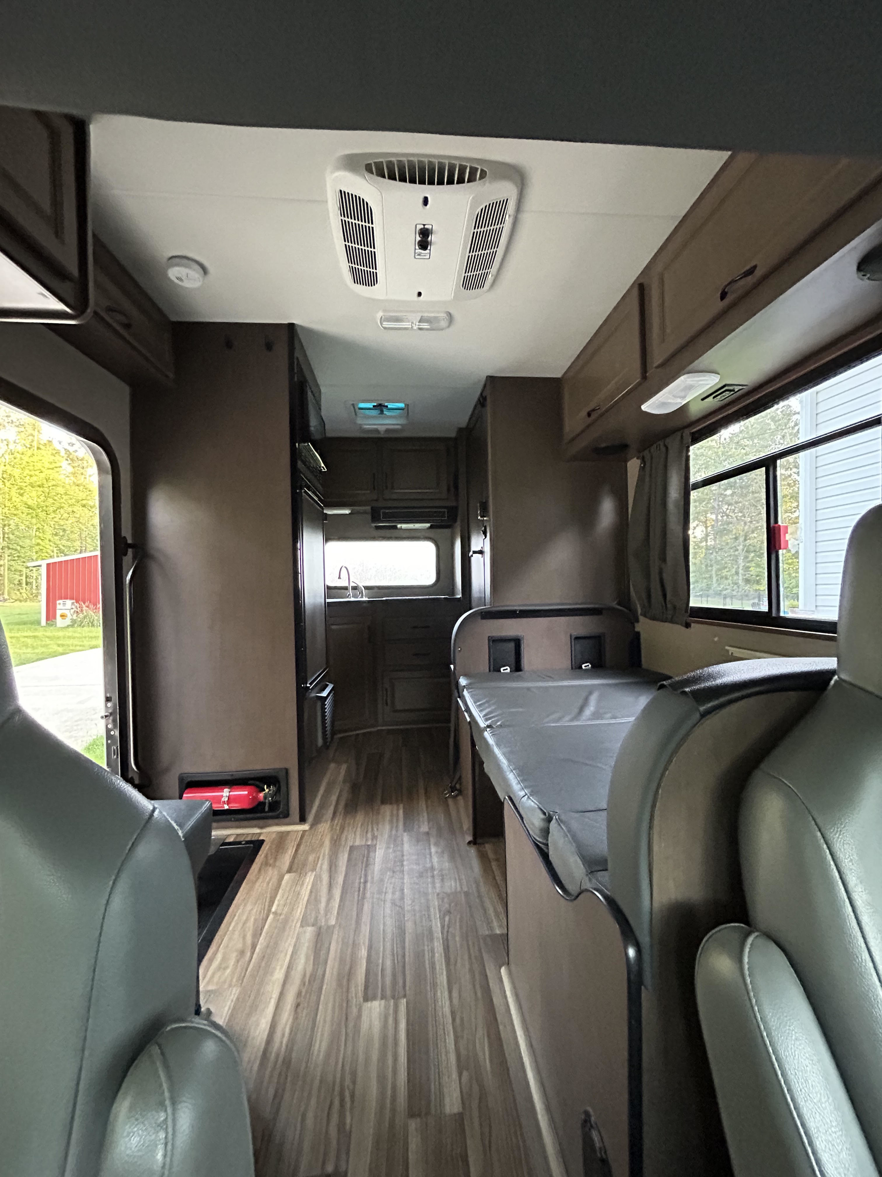 Spacious RV rental interior with kitchen, dinette, and wood-look flooring. View from front seats towards the back.. Thor Majestic 2020