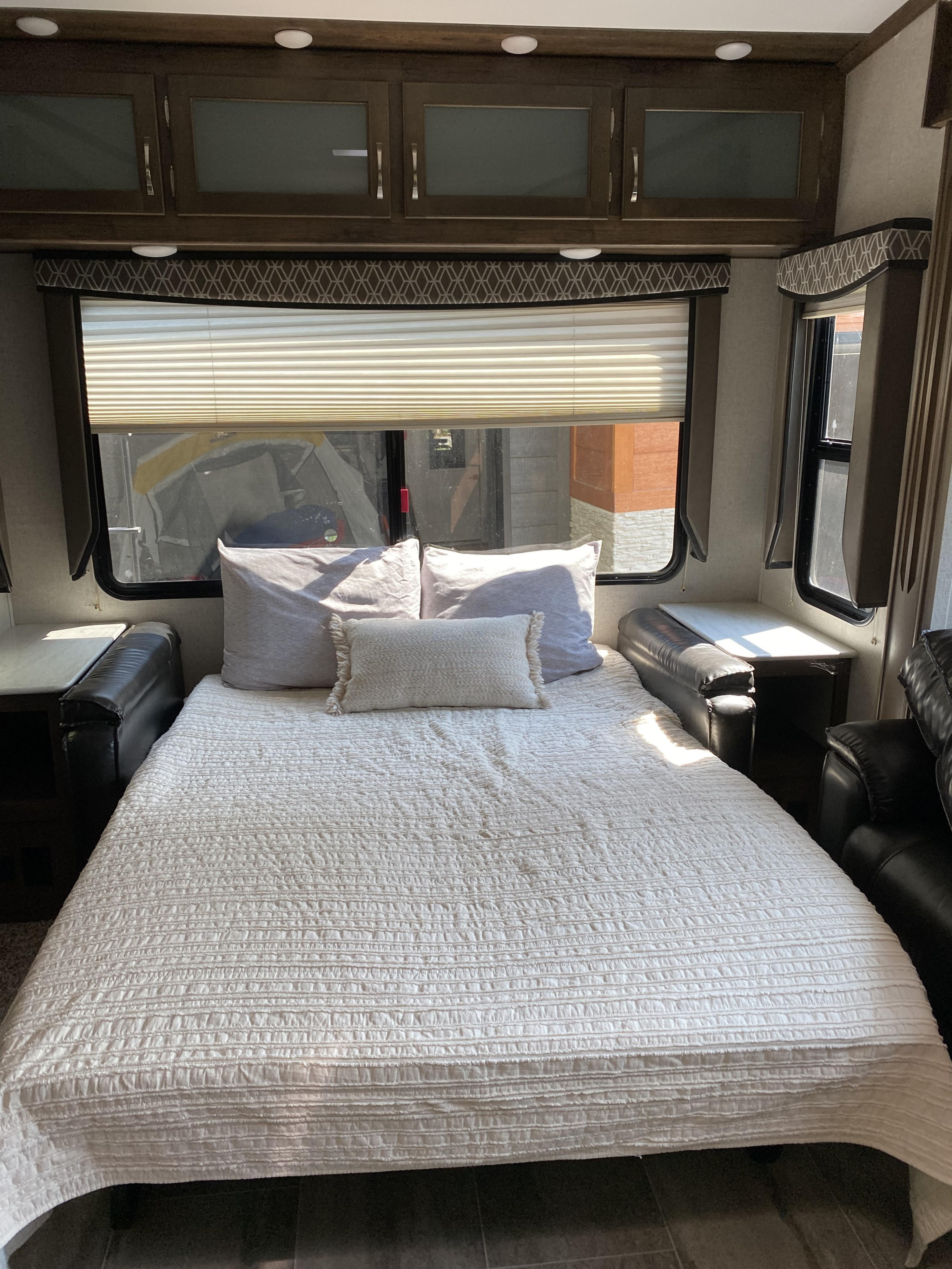 Cozy RV rental interior with a comfortable bed, overhead cabinets, and bright windows.. Dutchman Astoria 2019