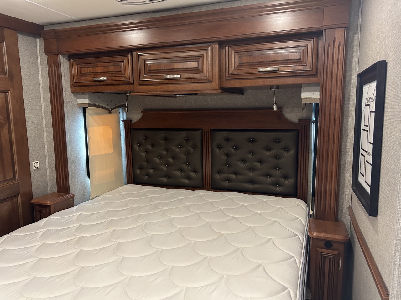 RV rental master bedroom featuring dark wood storage, tufted headboard, and a white mattress. Cozy and well-appointed.. Forest River Berkshire 2023