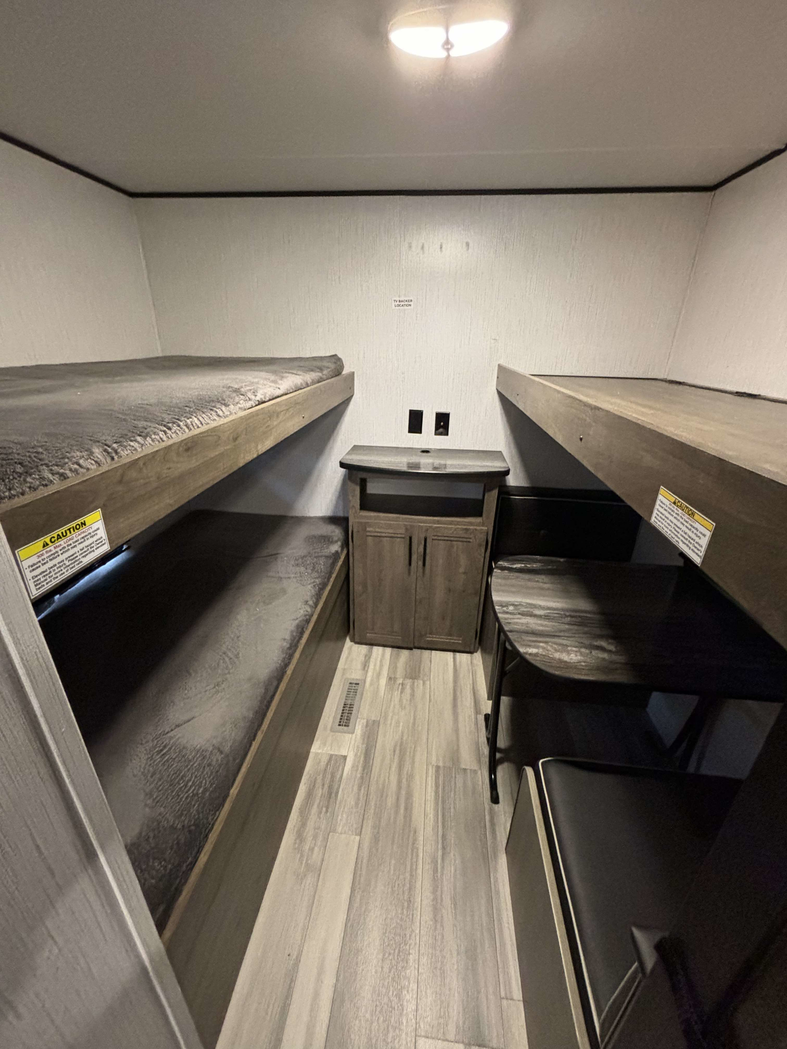 Efficient RV rental interior with comfortable bunk beds, a dinette, and storage, maximizing space for travel living.. Heartland RVs Pioneer 2022