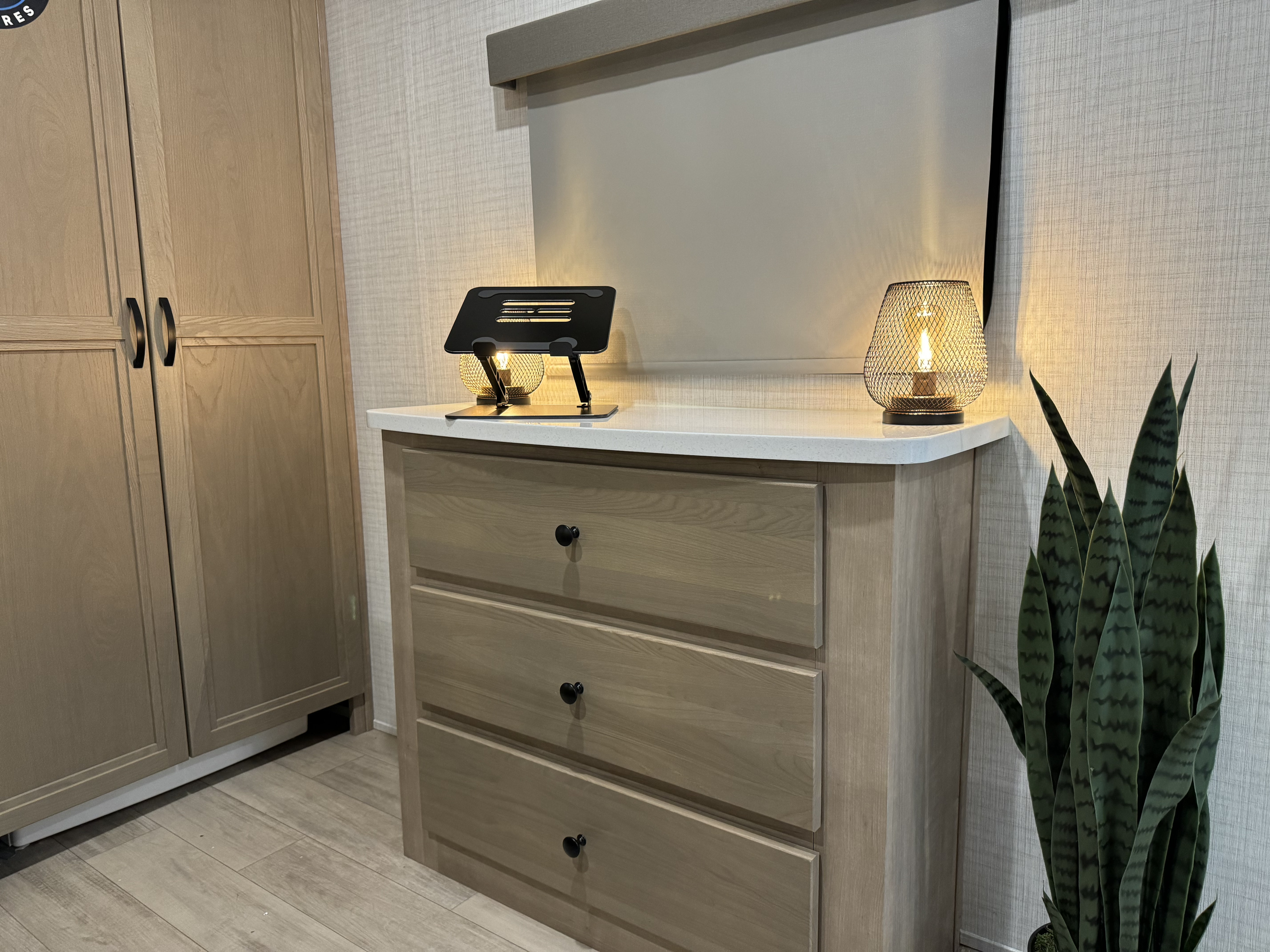 Spacious RV rental bedroom with practical storage: dresser, wardrobe, reading lamps, and a snake plant. Enjoy comfort.. Palomino Solaire 2024