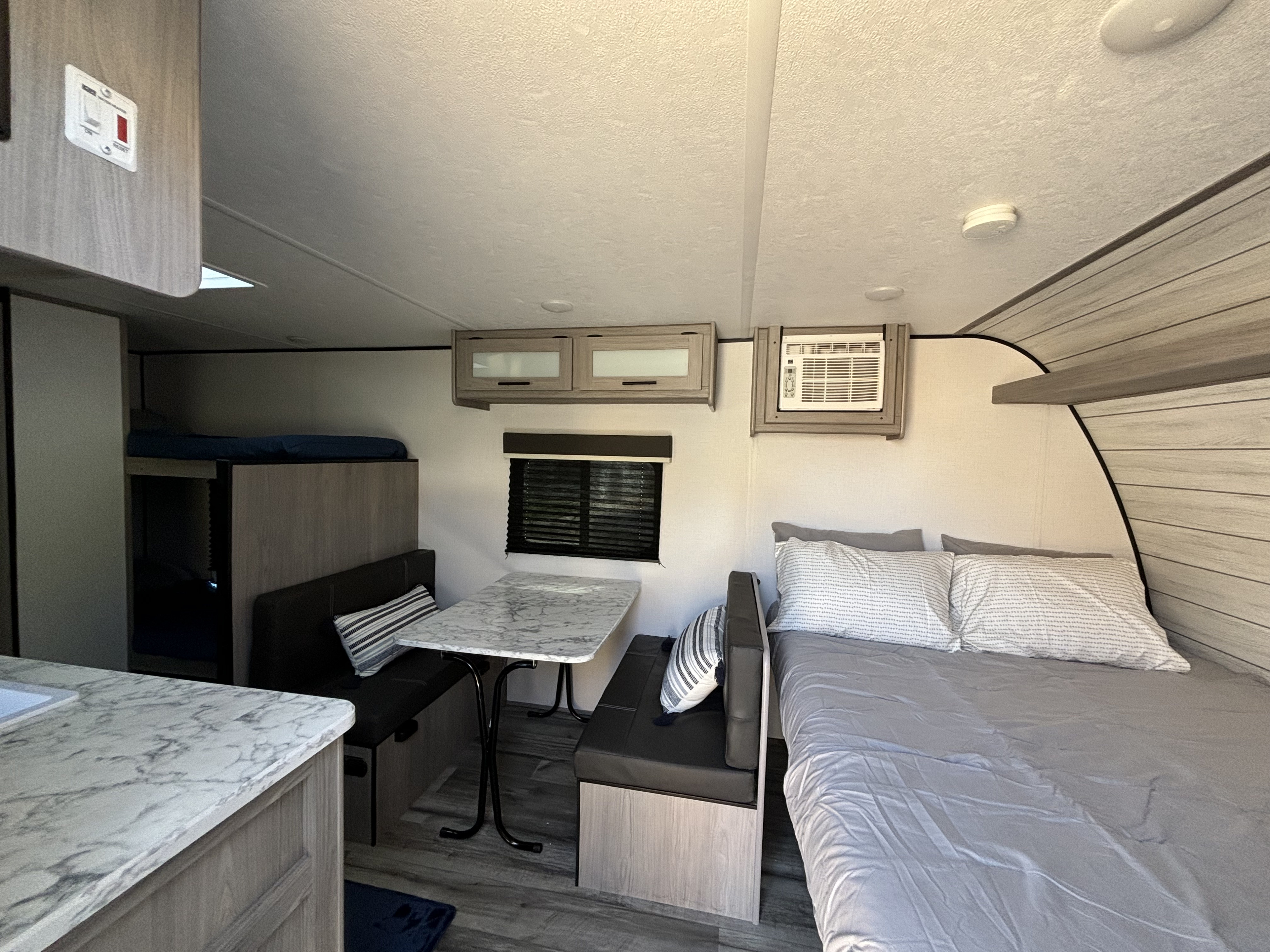 Inside this modern RV rental, see the main bed, dining booth, bunk beds, and kitchen counter for a comfortable stay.. Coleman 17B 2024