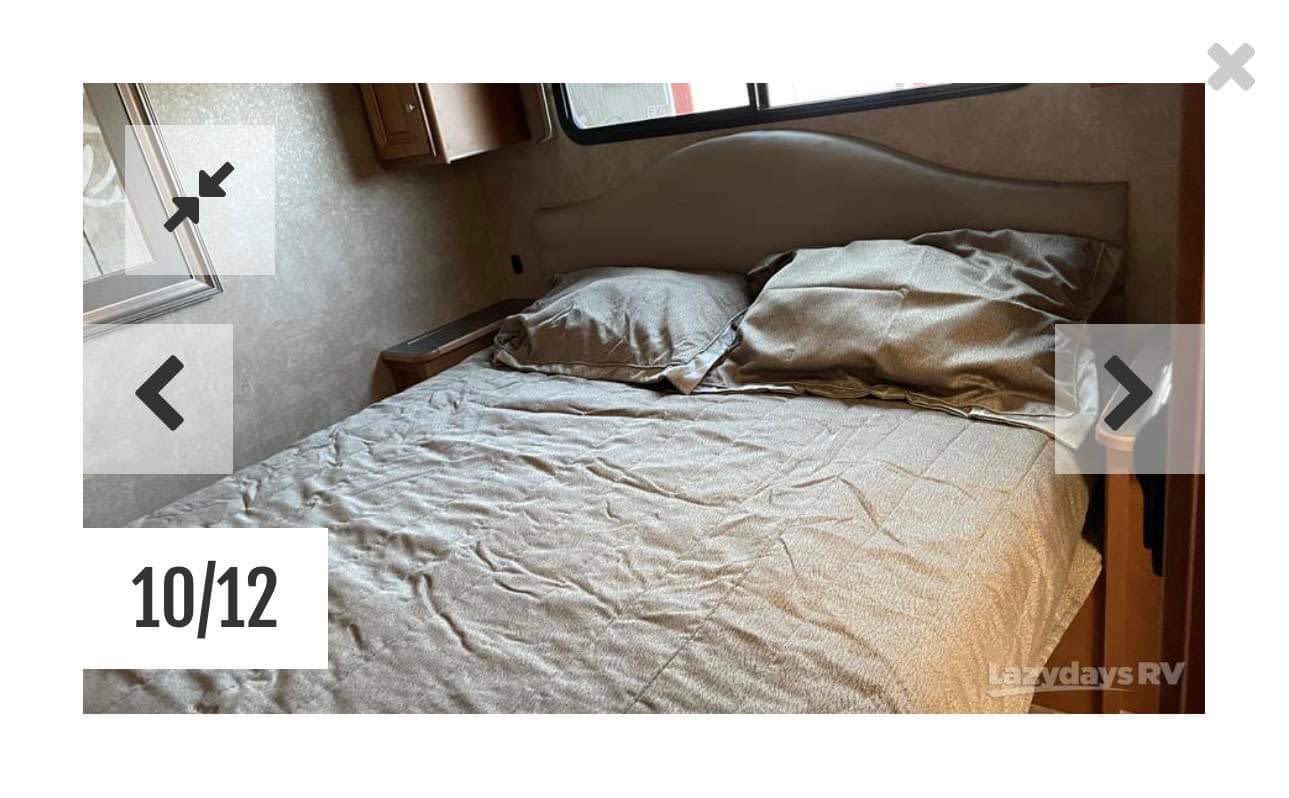 An inviting RV rental bedroom shows a neatly made bed with pillows, cabinetry, and a window for comfortable travels.. Winnebago Vista LX 2016