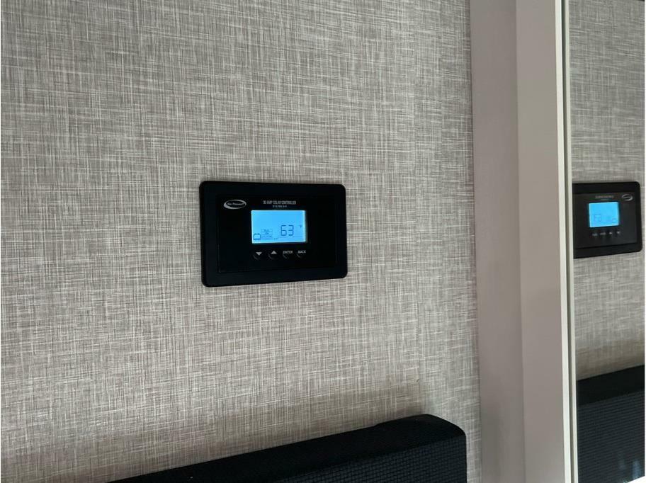 Solar charge controller displaying '63' on a textured wall in an RV rental, with its reflection in a mirror to the right.. Starcraft Autumn Ridge 2024