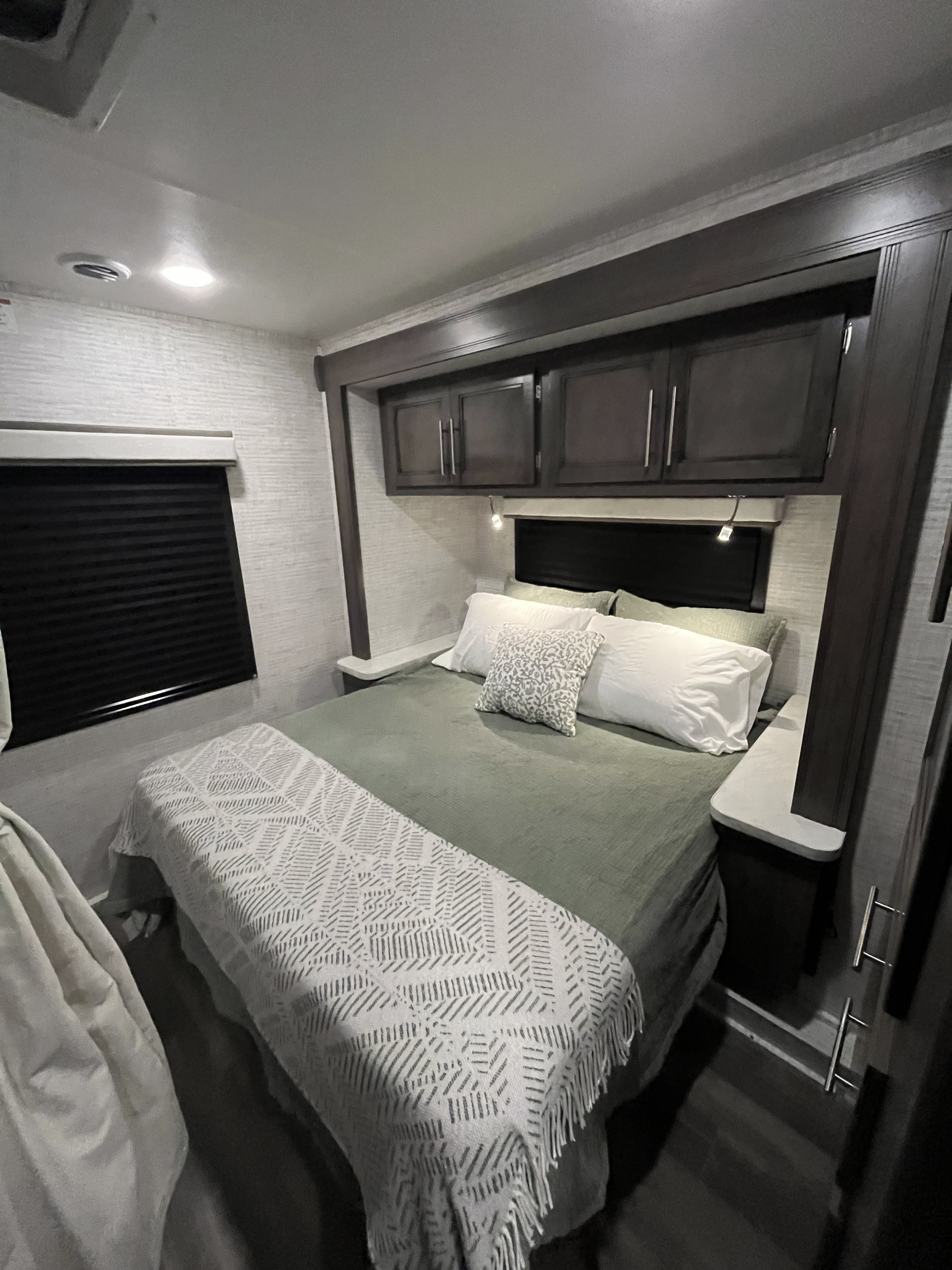 Explore this inviting RV rental bedroom. It features a neatly made bed, overhead storage, and ambient lighting, maximizing comfort.. Entegra Odyssey SE 2025