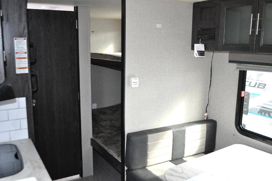 This RV rental interior features bunk beds, a dinette, and a kitchen area, offering comfortable living space.. Dutchmen Kodiak Cub 2018