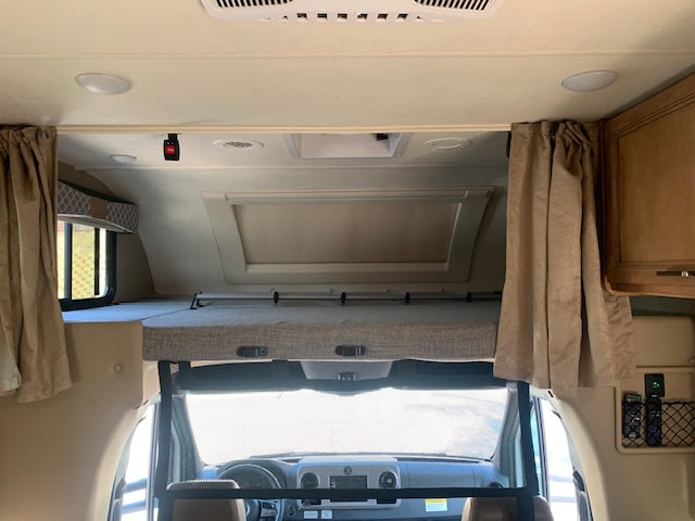 An RV rental interior, showcasing the spacious cab-over bunk bed and front driving area below.. Thor Quantum 2019