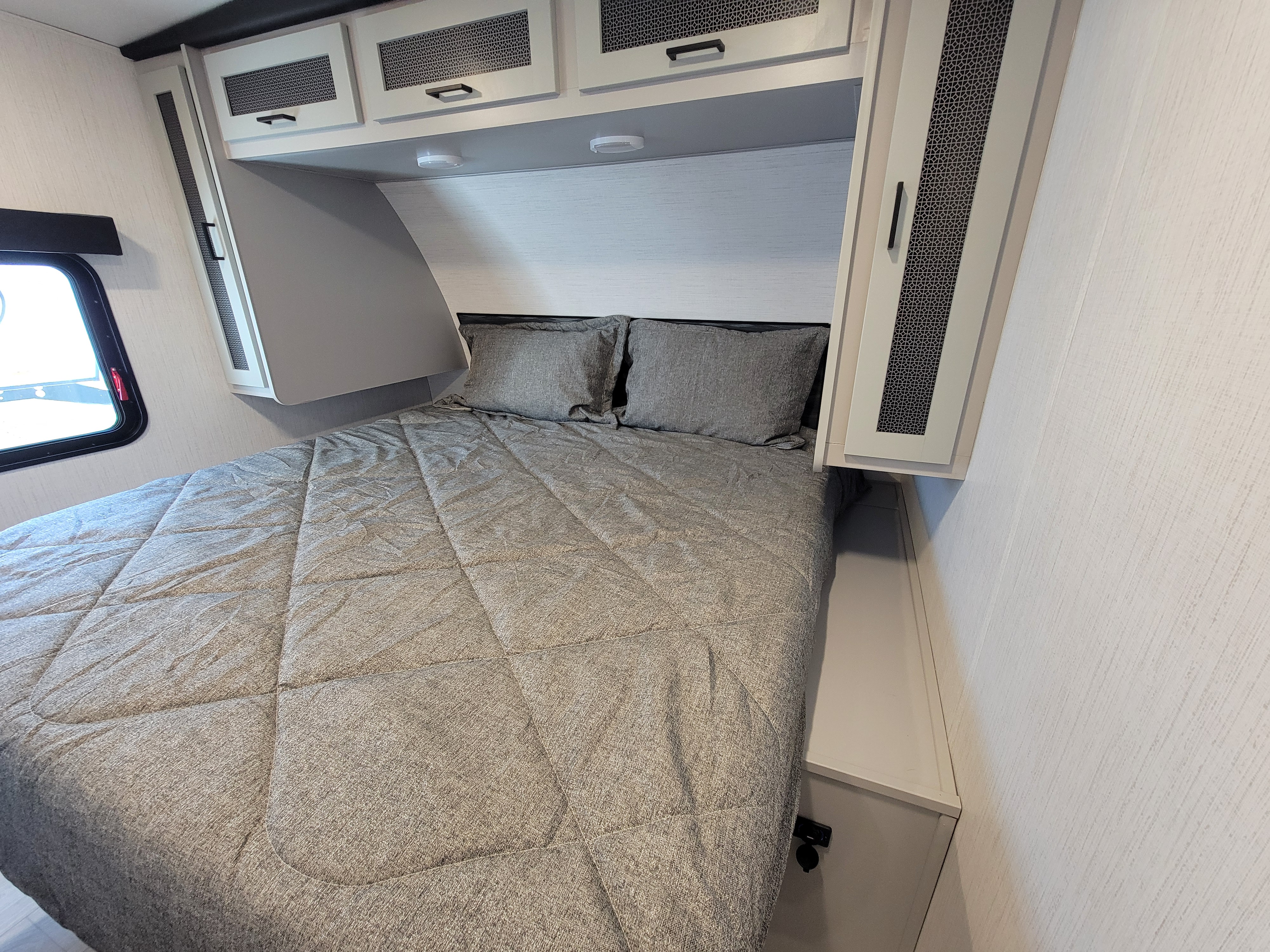 Modern RV rental bedroom featuring a cozy bed, overhead storage, and stylish finishes for your journey.. Heartland RVs North Trail 2023