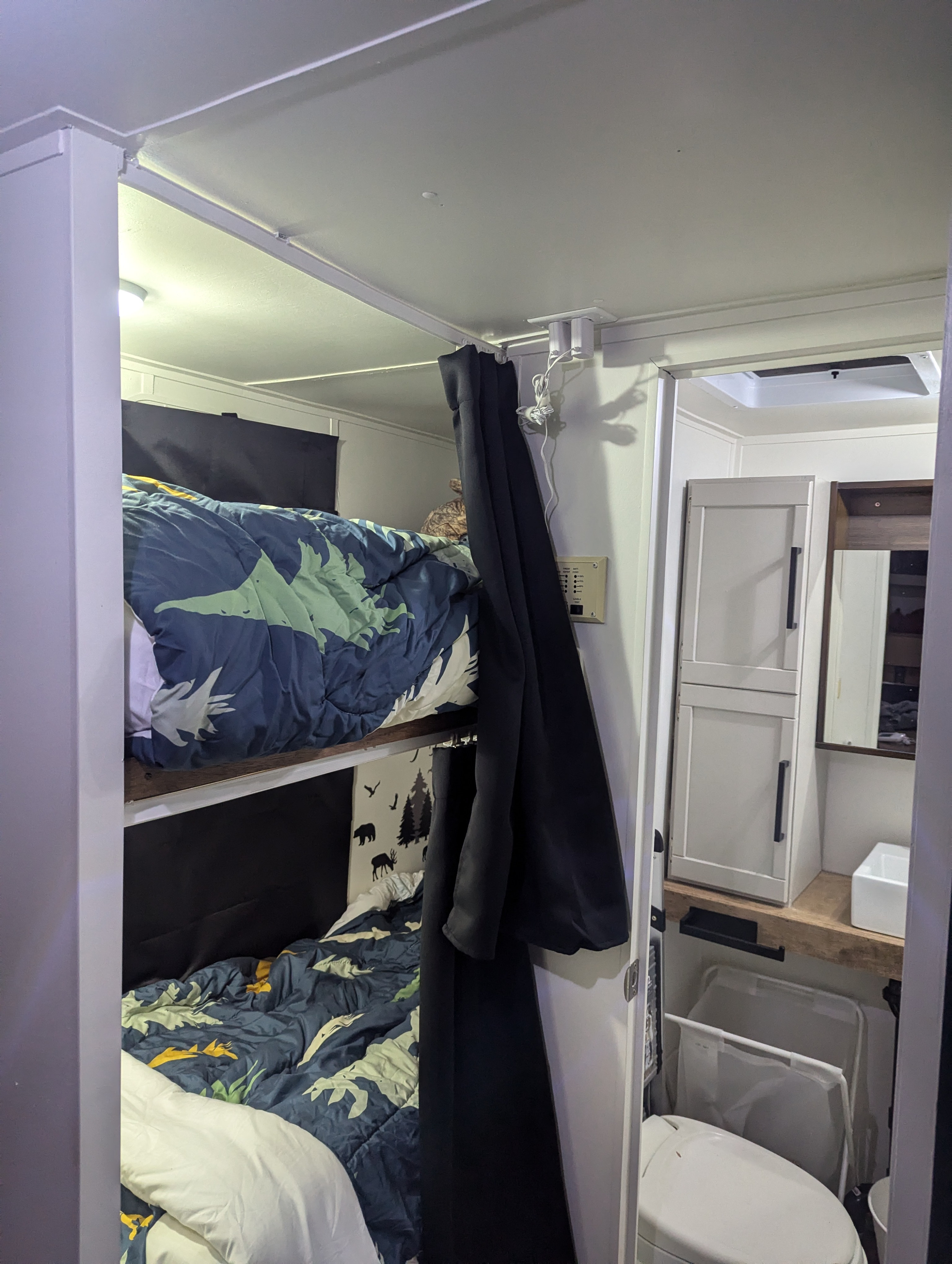 Cozy RV rental interior with bunk beds, a sleeping cat peeking out, and a compact bathroom. Ideal for tiny living.. Gulf Stream Ameri-Lite 2004